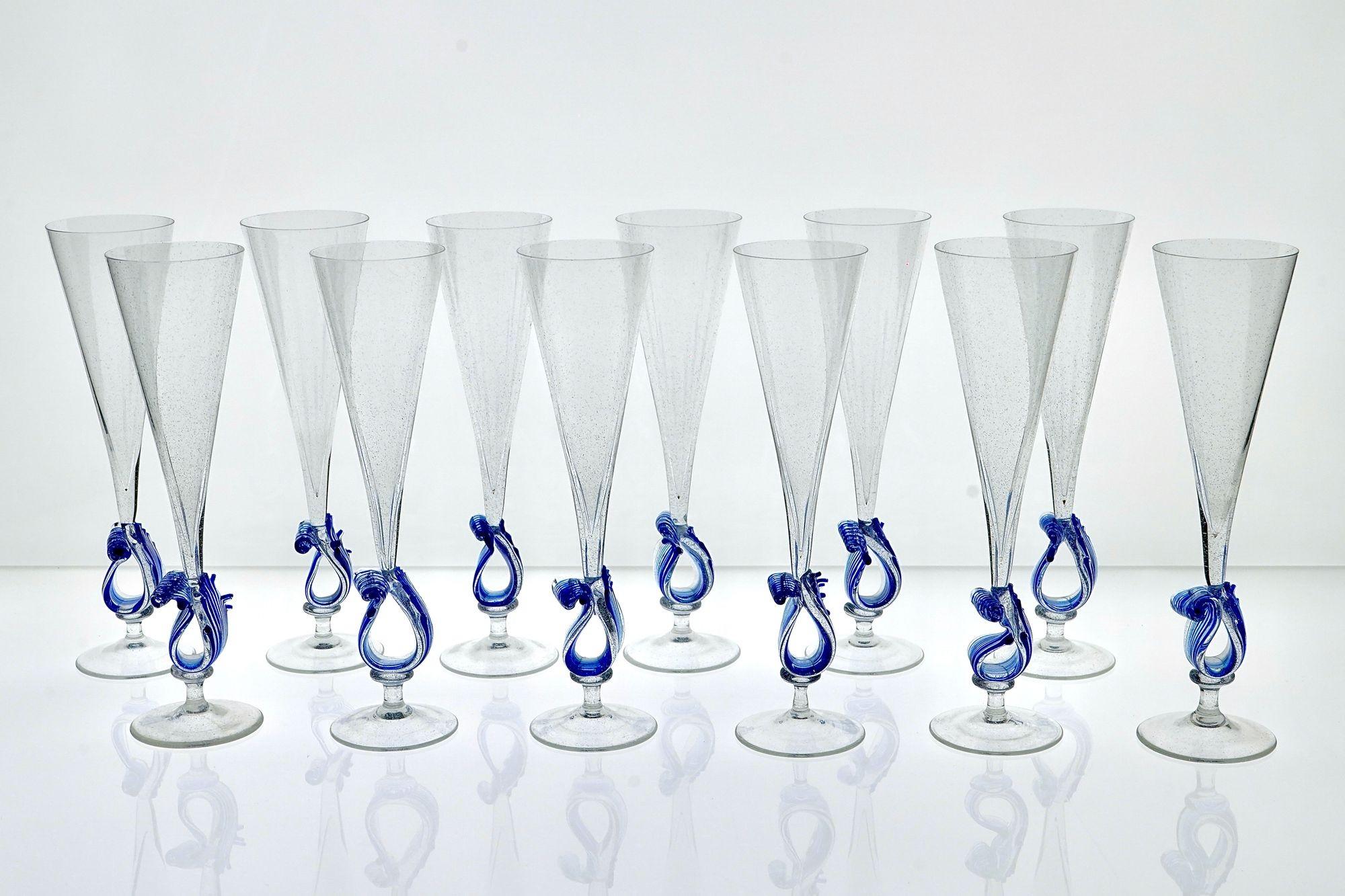 Complete unique set of flutes from Cenedese. 
The clear part shows a light pulegoso, made to give an antique look. The base carries a hand made wave with stripes of cobalt glass beads.
Pristine condition. From Cenedese inventory. Never