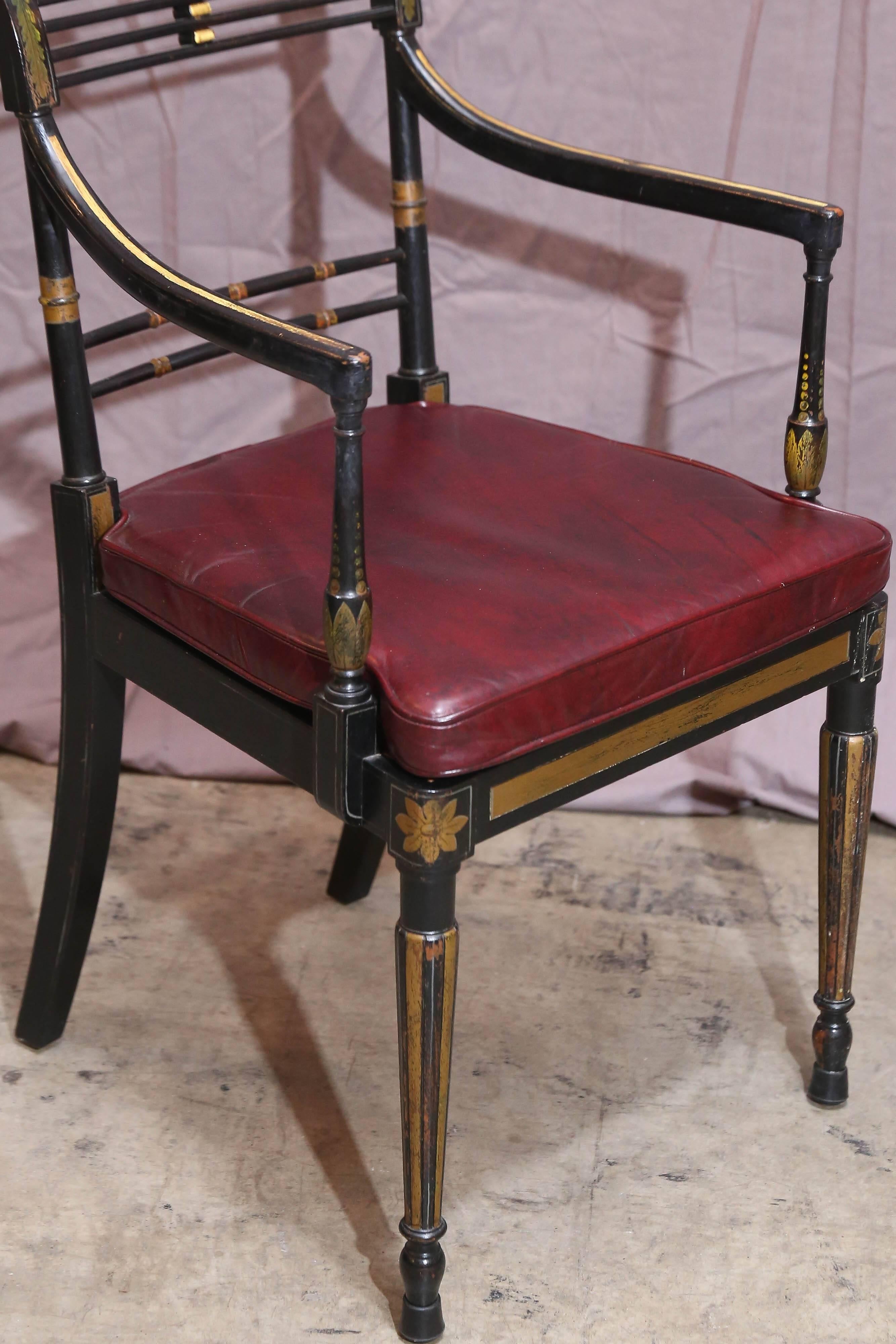 Set of black painted period English Regency armchairs are heavily stenciled in gold leaf with an acanthus leaf design. Legs are fluted and have carved detail at foot and new caned seats with leather seat pads.

front seat width 19.5