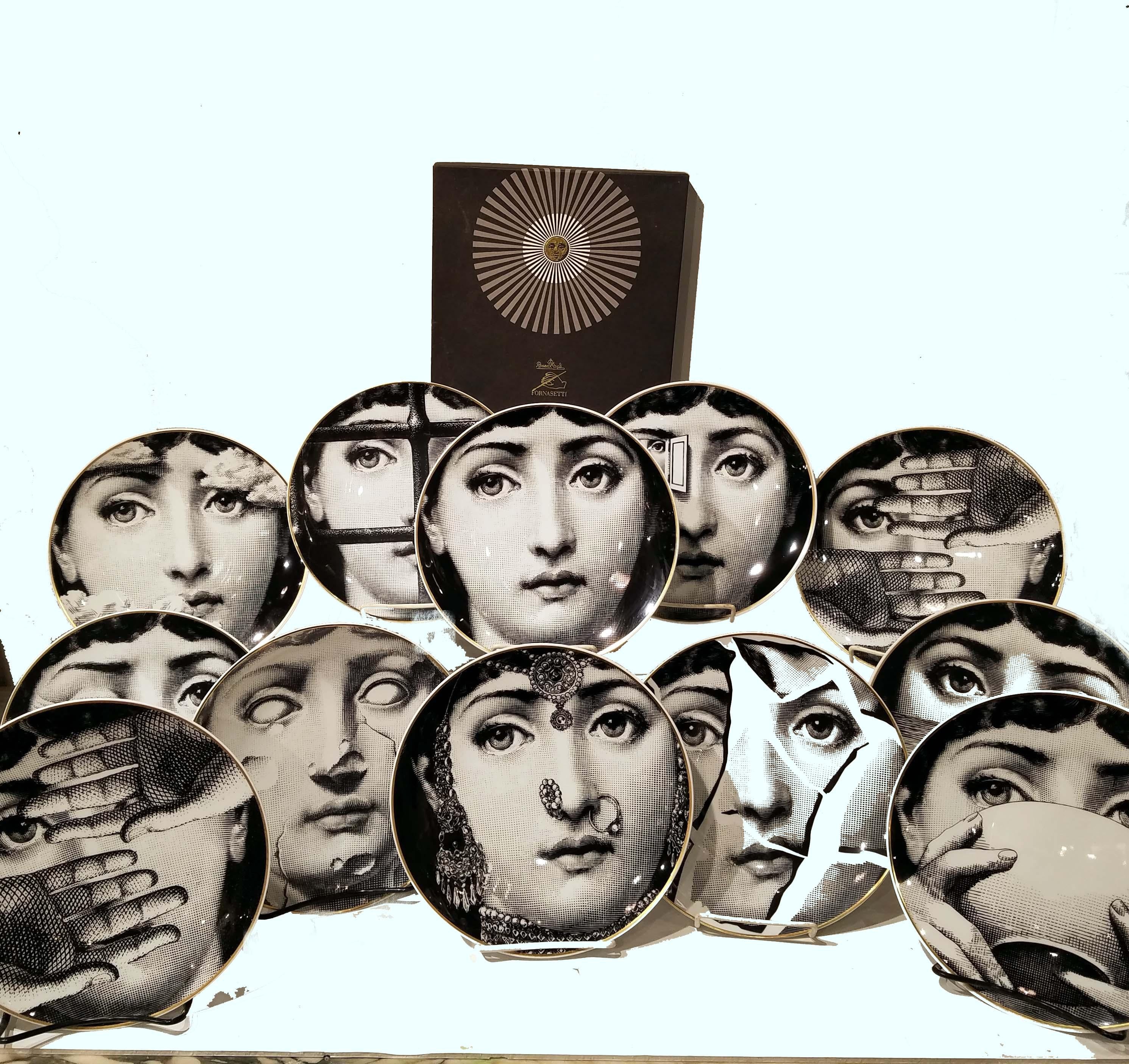 A large set of 12 displaying porcelain plates with surrealism designs by Piero Fornasetti for Rosenthal, an iconic series from 'Temi e variazioni' (“Themes and Variations”). Each with the original box included, circa 1980. These plates were made for