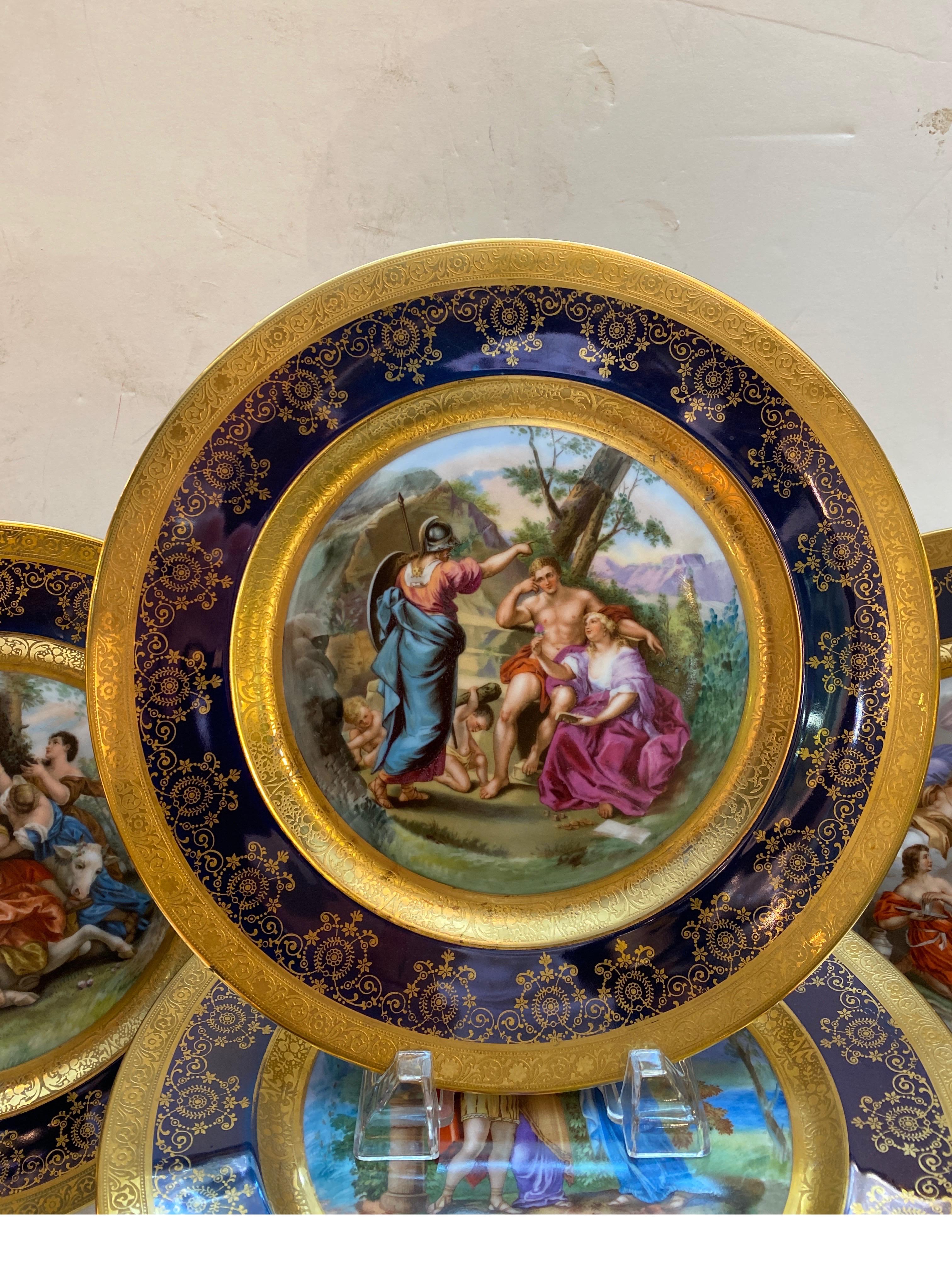 An elaborate set of 12 Royal Vienna porcelain hand painted cabinet plates with cobalt and gold borders. The plates measure 10.75 inches in diameter and depict 12 different allegorical scenes in vibrant colors. No breaks or repairs with minimal to no