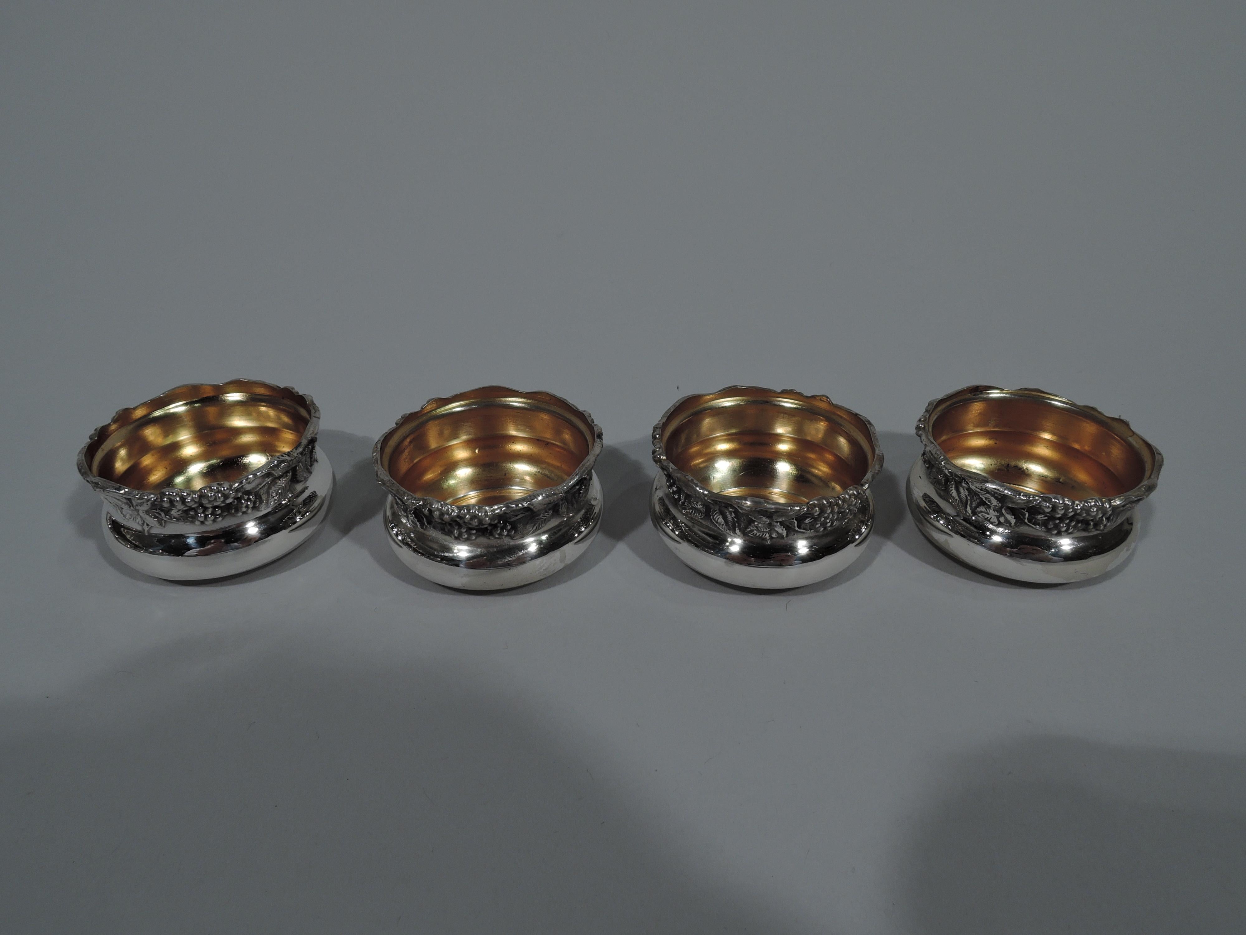 Set of 12 pretty Art Nouveau sterling silver open salts. Made by Webster in N. Attleboro, Mass., circa 1900. Each: Bellied bowl on inset foot ring. Rim has tooled leaves and berry bunches. Interior gilt. Hallmarked. Total weight: 5.3 troy ounces.