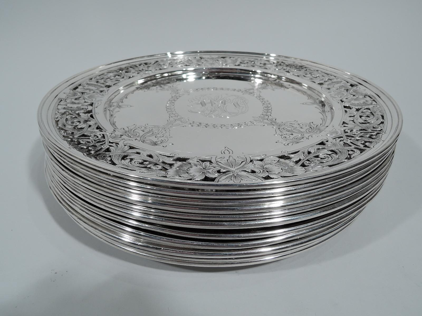 Twelve American Edwardian Art Nouveau sterling silver dinner plates. Each: Round and solid well engraved with interlaced monogram set in wreath surrounded by four interlaced leafing C-scrolls. Pierced shoulder with engraved flowers and scrolling