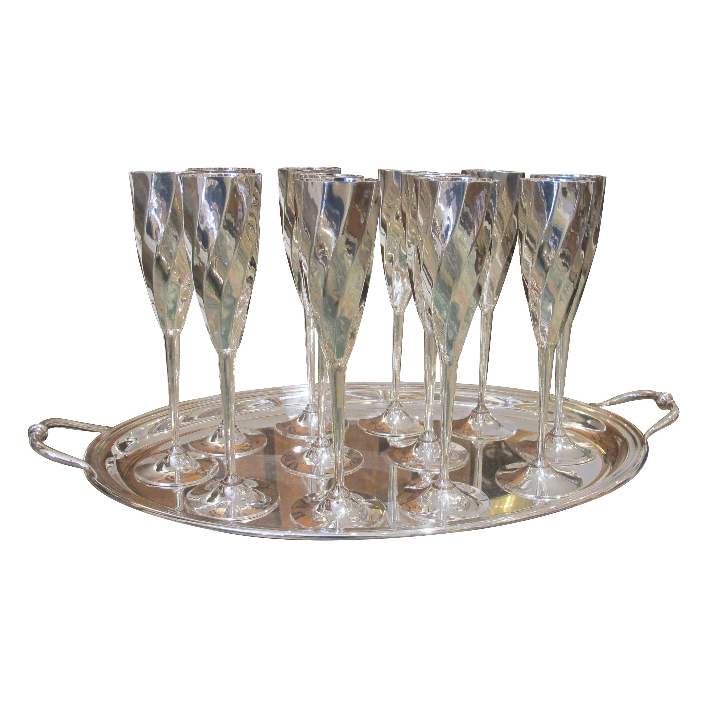 Questo splendido ed elegante set comprende 12 flute da champagne placcati in argento e un vassoio da portata placcato in argento coordinato. Ogni flute presenta un bellissimo design contorto e scanalato che cattura la luce. Il vassoio è marchiato