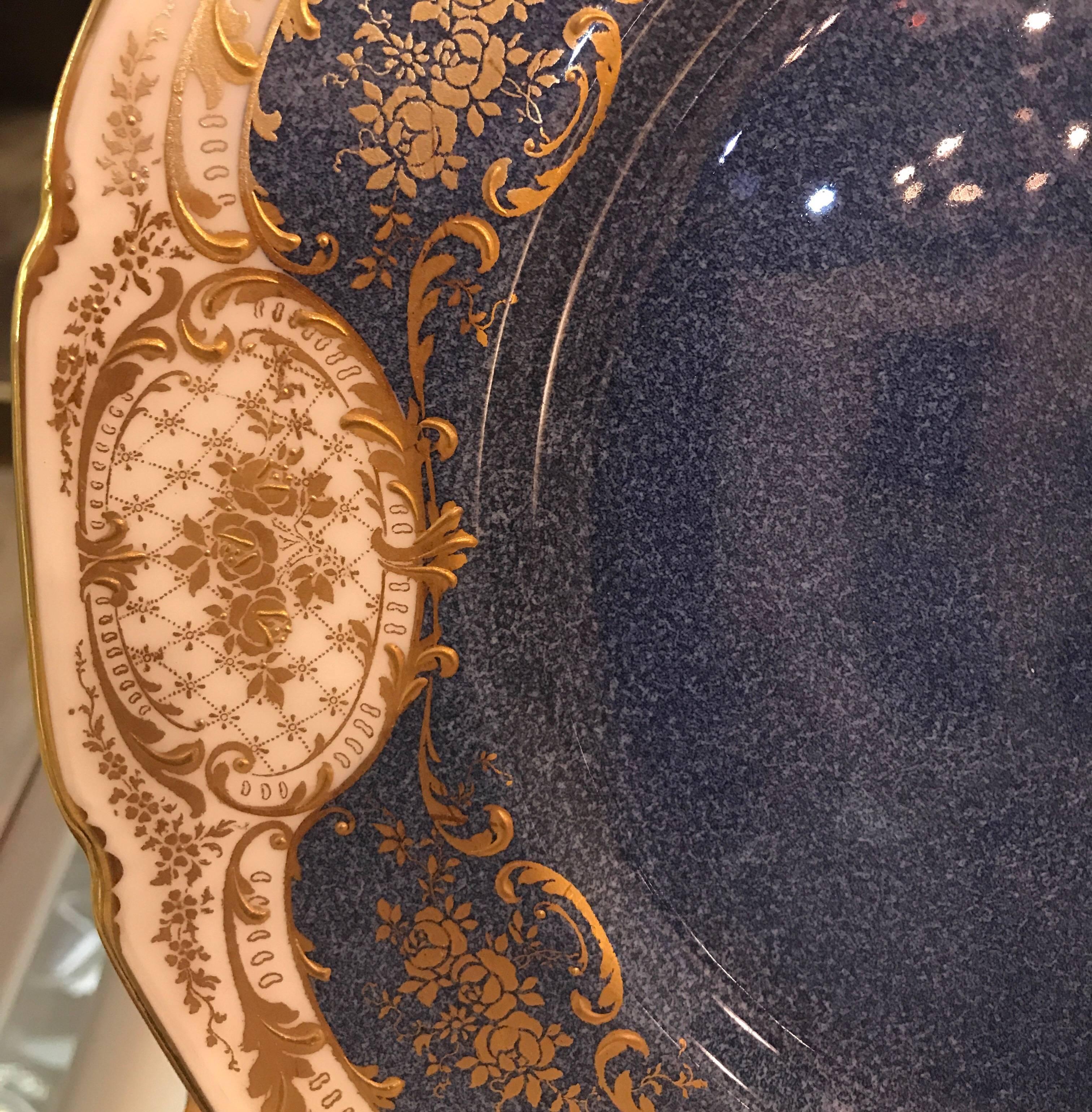 A set of 12 Edwardian raised gilt service plates made by Royal Doulton. The hand stippled cornflower blue centres surrounded by delicate lacy raised gilt borders. The plates are signed with the artist code for Herbert Benneley and the year mark of