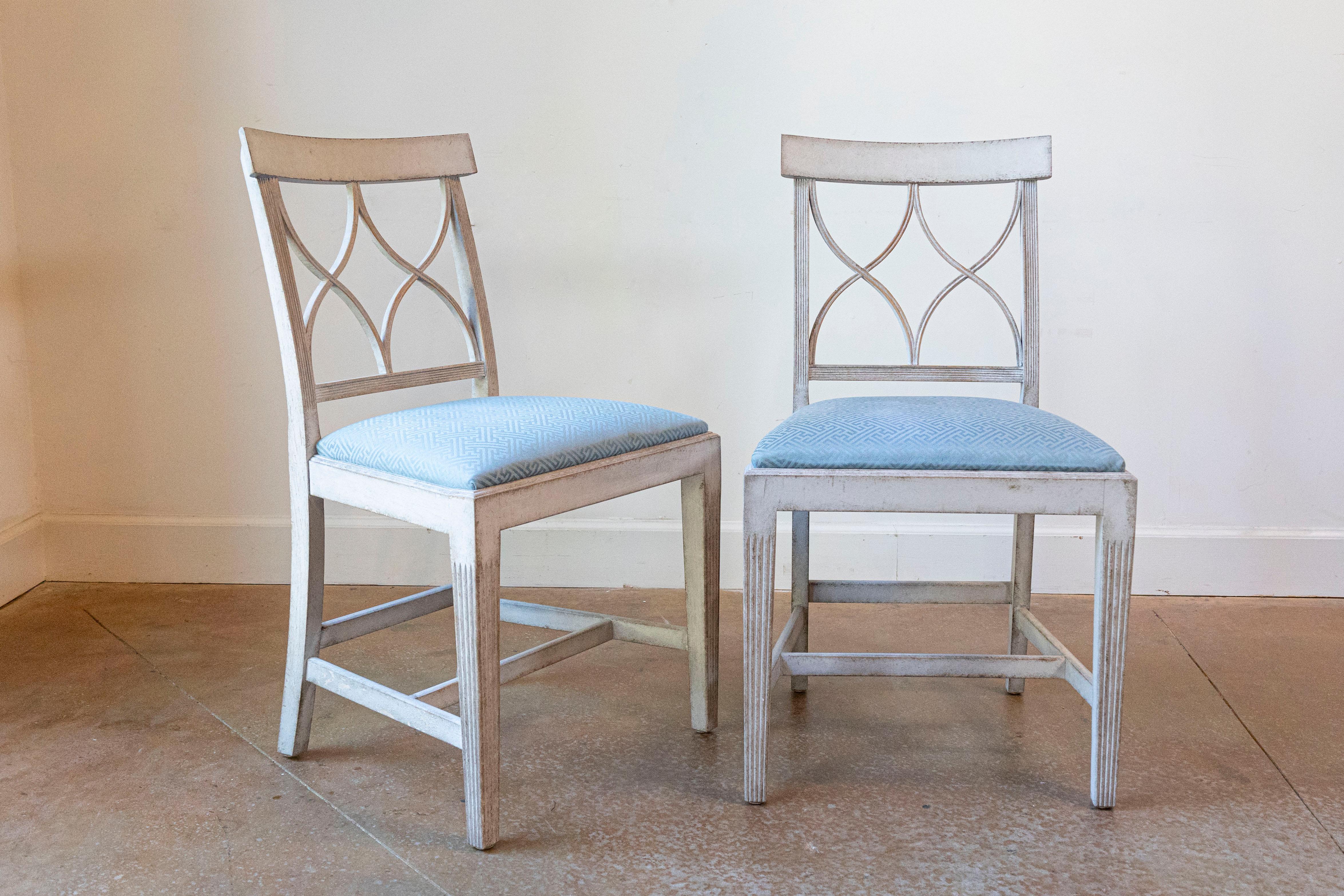 Priced Each - 8 Swedish dining room side chairs from the early 20th century, with new upholstery. Created in Sweden during the early years of the 20th century, each of this set of side chairs features an open back pierced with sinuous motifs and