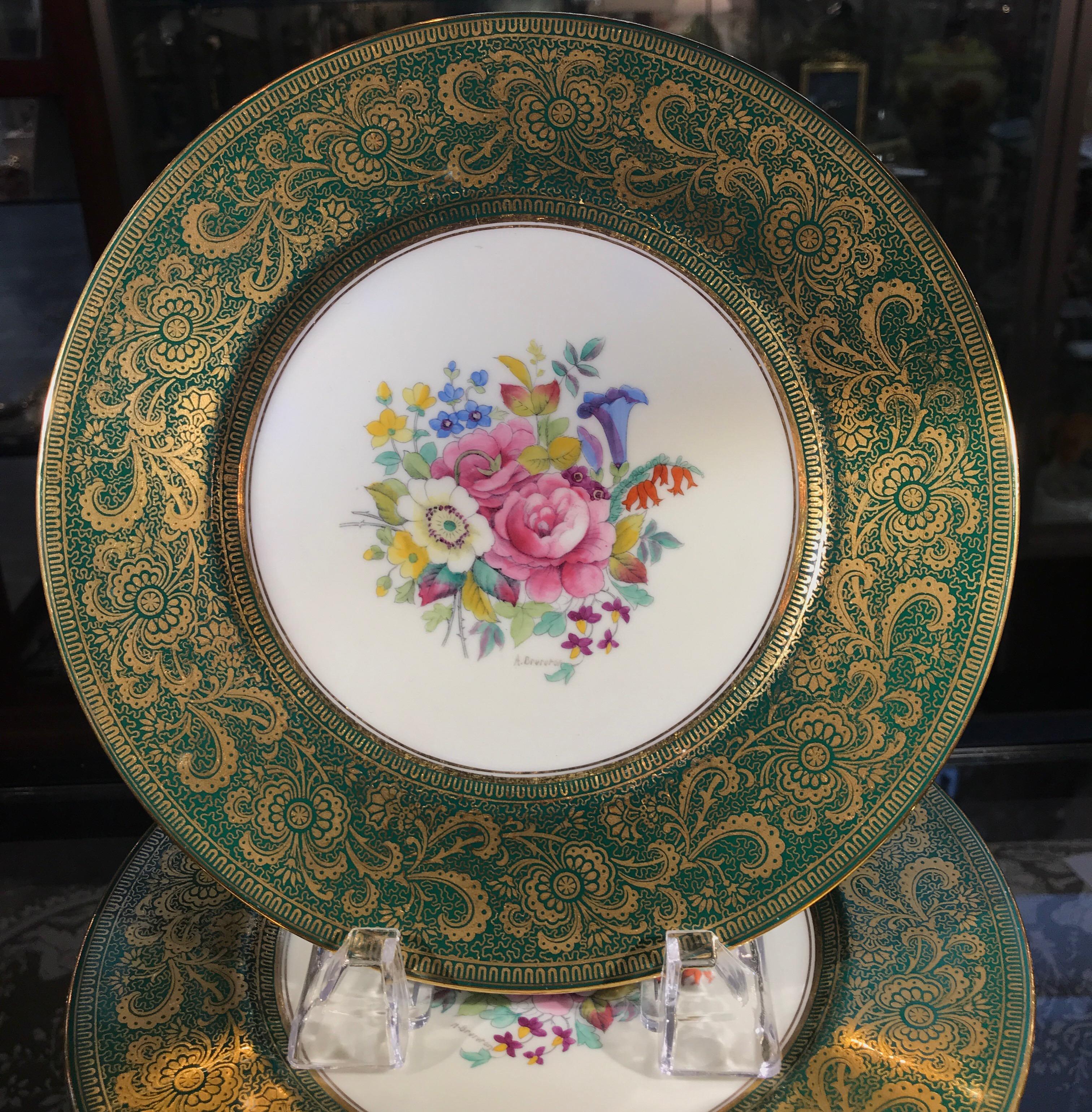A set of 12, 9 inch accent plates for Tiffany & Co. made by Cauldon in England, circa 1910. The elaborate gold scrolling borders with Harrods green background with hand painted central floral bouquet signed by the artist A. Brereton on the lower