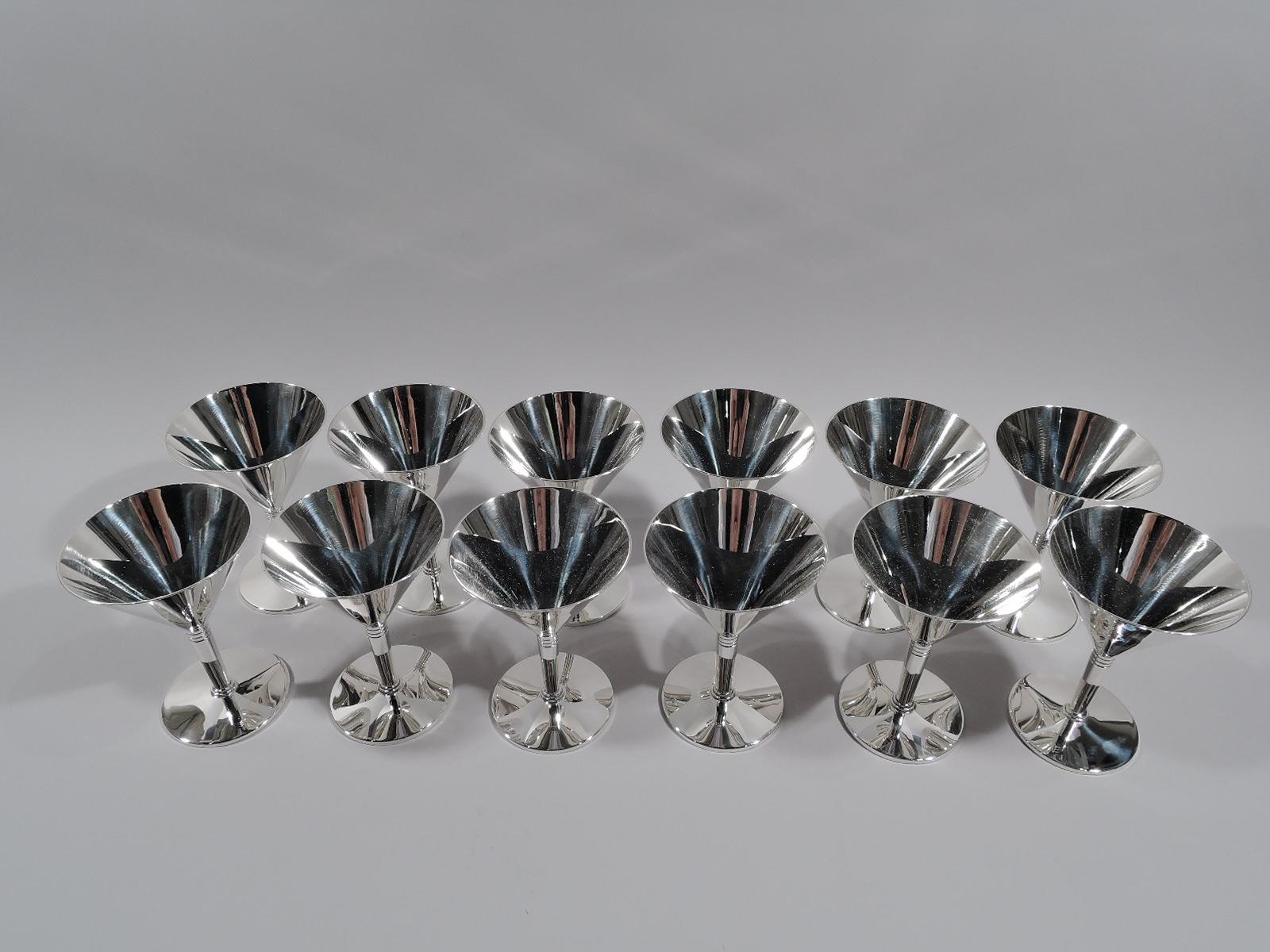 Set of 12 Art Deco sterling silver cocktail cups. Made by Tiffany & Co. in New York, ca 1935. Each: Conical bowl on cylindrical stem terminating in stepped base mounted to flat round foot. Tooled bands on stem. Spare and functional geometry. Fully