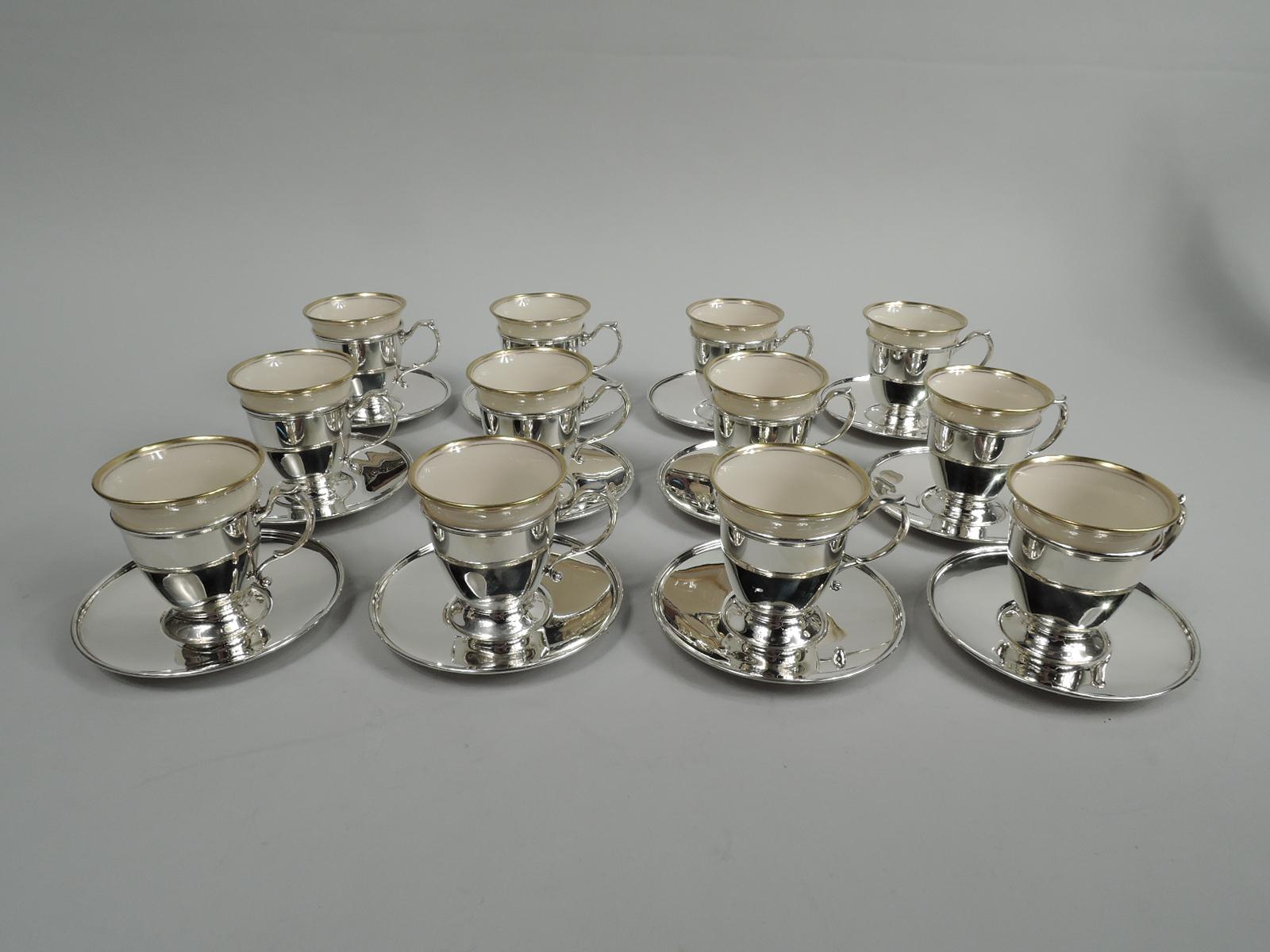 Set of 12 Edwardian sterling silver demi-tasse holders and saucers. Made by Tiffany & Co. in New York, ca 1914. This set comprises 12 holders and 12 saucers. Each holder: Conical with spread foot and capped s-scroll handle. Each saucer: Well with