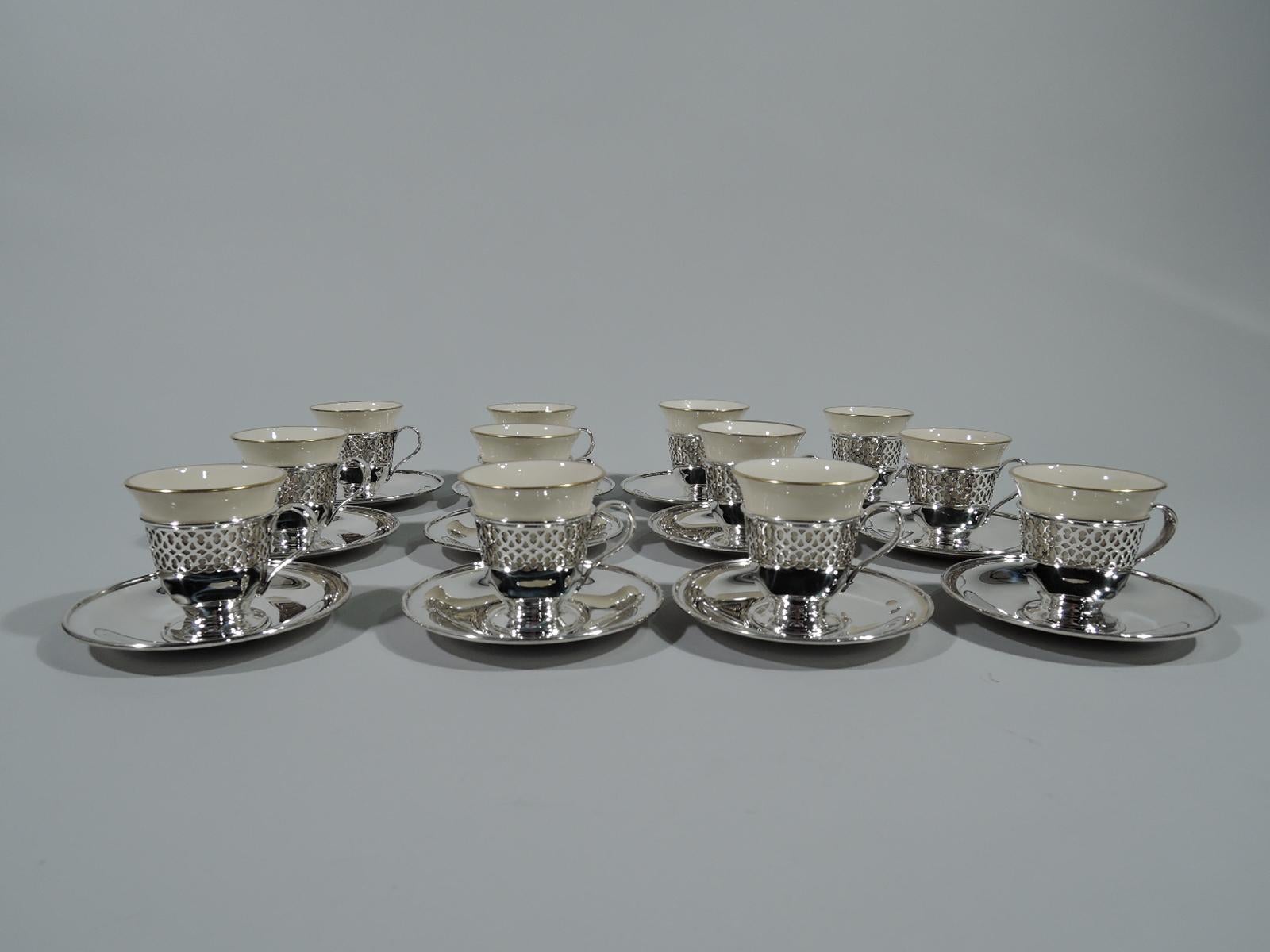 Set of 12 Edwardian sterling silver demitasse holders and saucers. Made by Tiffany & Co. in New York. Each holder: Tapering with high-looping handle and open and raised foot. Top part has pierced geometric ornament. Each saucer: Round and tapering