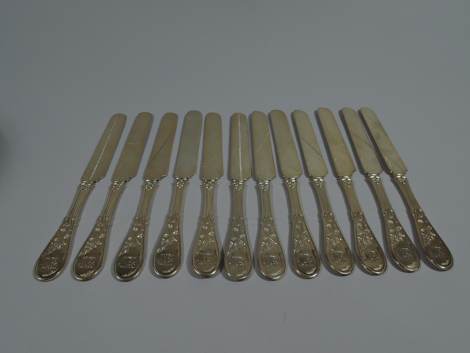 Set of 12 parcel gilt sterling silver dessert knives in Japanese pattern. Made by Tiffany & Co. in New York. Each: Flat handle with reeding that terminates in flower stems on terminal. On terminal front reverse-gilt bird. On terminal back interlaced