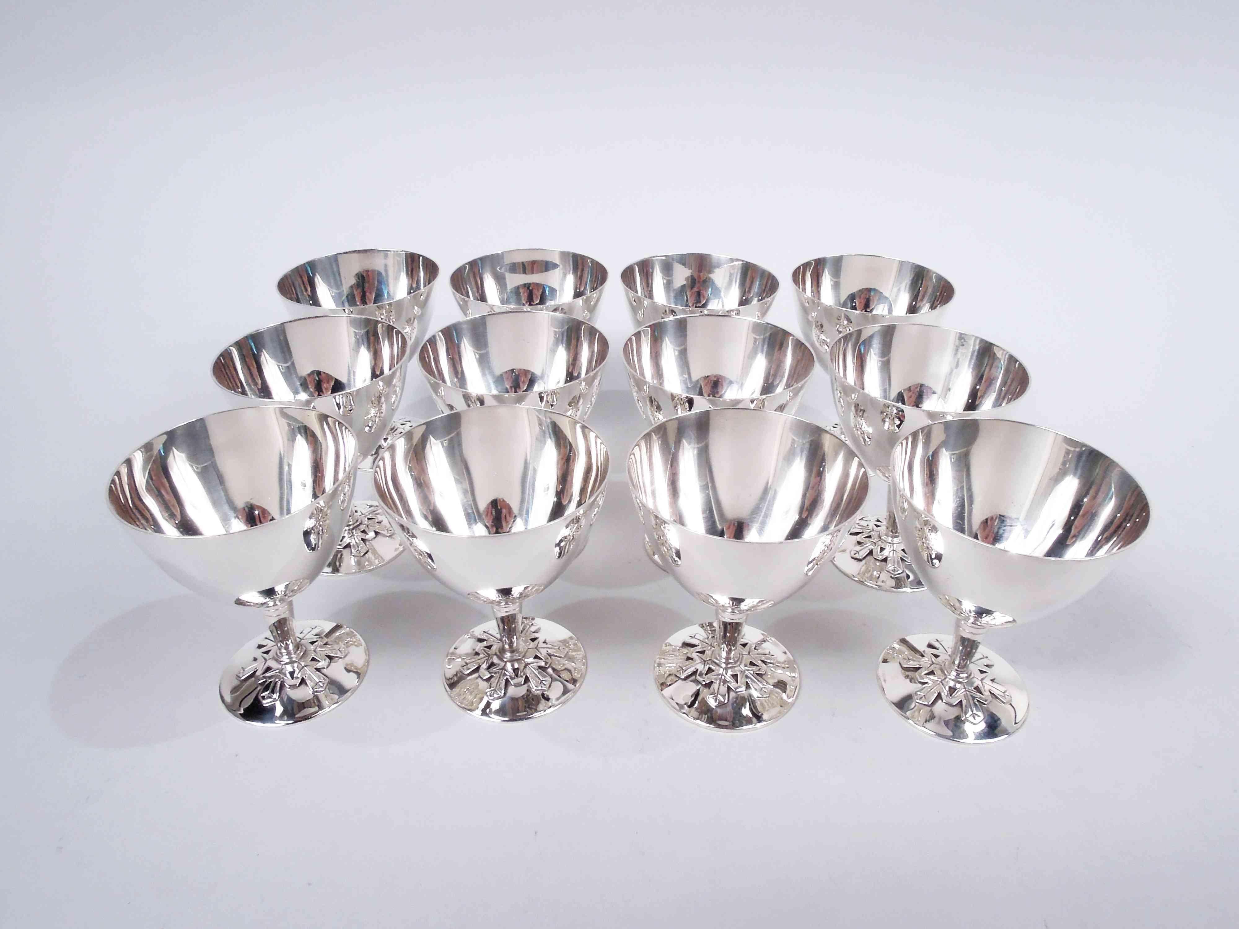 Set of 12 Midcentury Modern sterling silver cocktail cups. Made by Tiffany & Co. in New York. Each: Curved conical bowl on tapering columnar stem with incised bands. Foot round and raised with applied cutout snowflake. A snowflake motif but not for