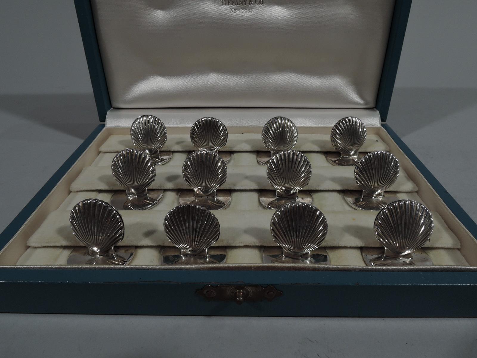 Set of 12 modern classical sterling silver place card holders. Made by Tiffany & Co. in New York. Each: double sided scallop shell mounted to flat circular base. In original leather-bound case with silk and velvet interior, and gilt maker's stamp.