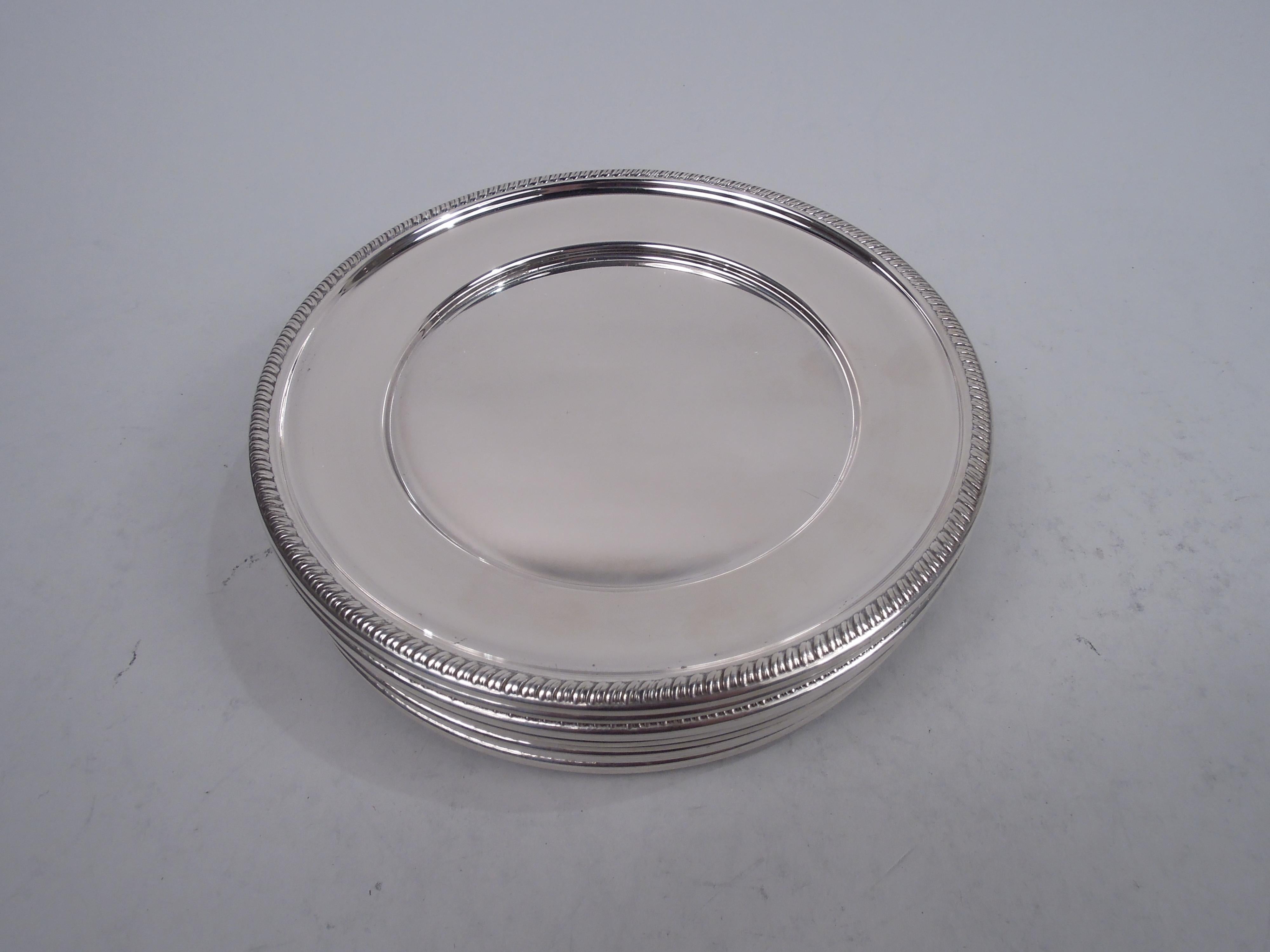 Set of 12 traditional Georgian sterling silver bread and butter plates. Each: Well with tapering shoulder and embossed gadrooned rim. Fully marked including stamp for Hunt Silver Co., a maker active in Chicago and New York in the 1930s-40s, and no.