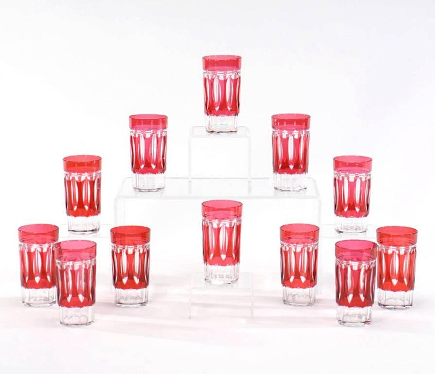 A lovely set of 12 Val St. Lambert crystal tumblers cut to clear in a rare Art Deco pattern. The clean lines with panel cut base are contrasted with the vibrant cranberry overlay. These are very versatile and perfect for any table setting and cold