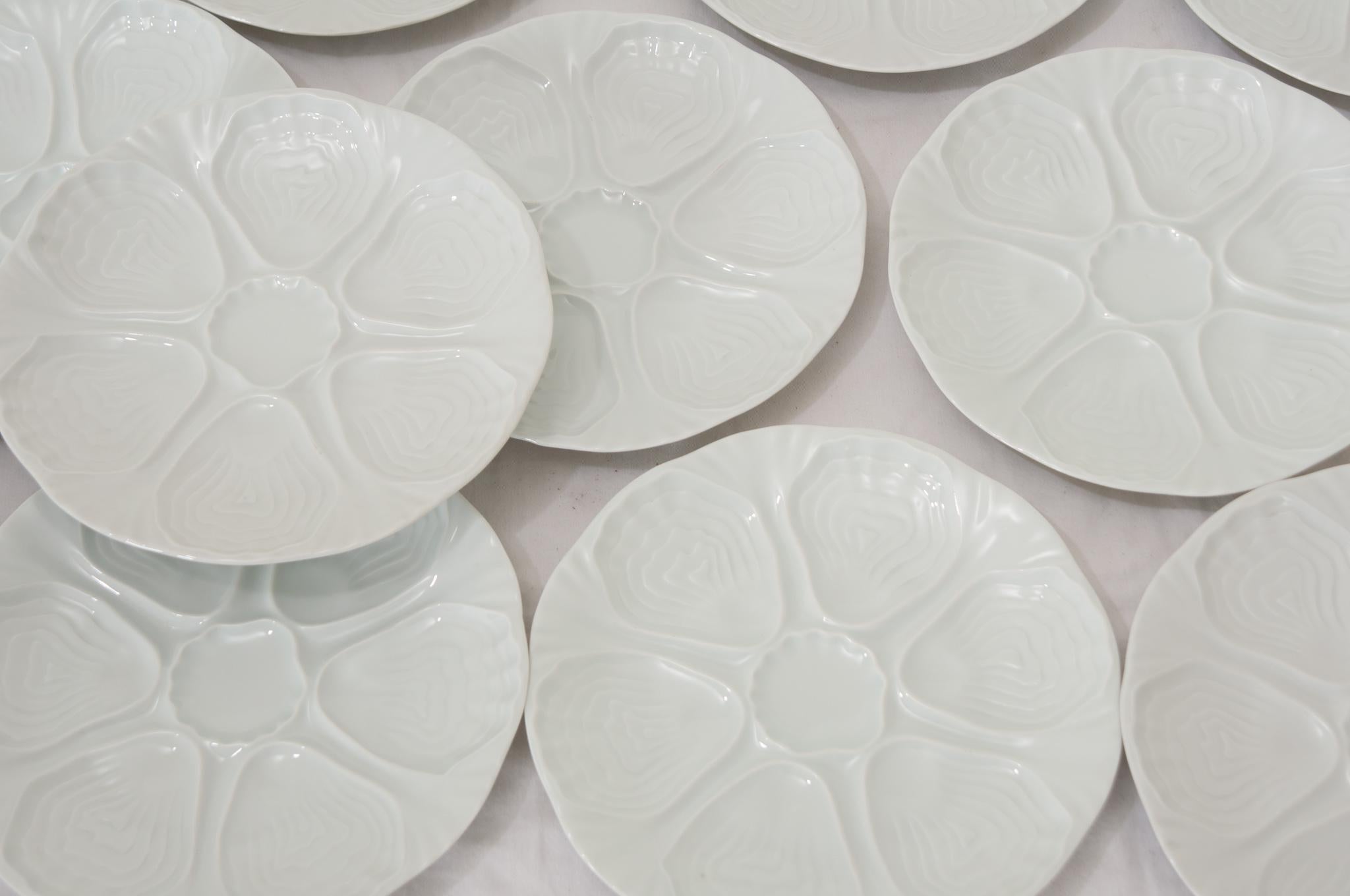 An elegant set of twelve French white oyster plates made by Hutschenreuther Porcelain in Germany during the 20th Century. These plates are fabulous with glossy molded and shaped centers and scalloped edges. The maker’s stamp can be found on the