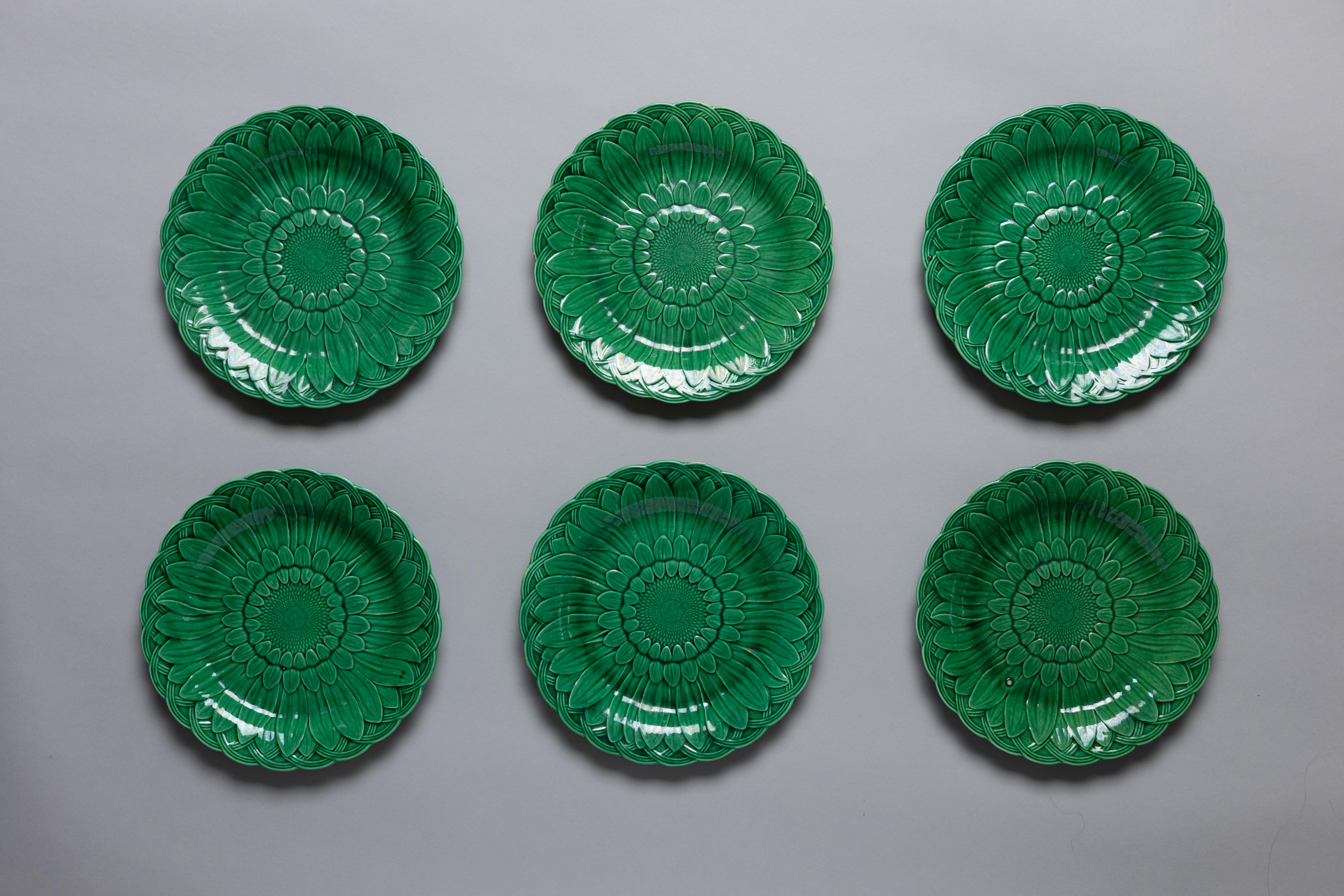 Set of 12 green majolica glazed dinner plates in the ‘Sunflower’ pattern by Wedgwood, made circa 1880.

The sunflower, alongside the calla lily and peacock feather, became an emblem of the late nineteenth-century Aesthetic Movement. Oscar Wilde
