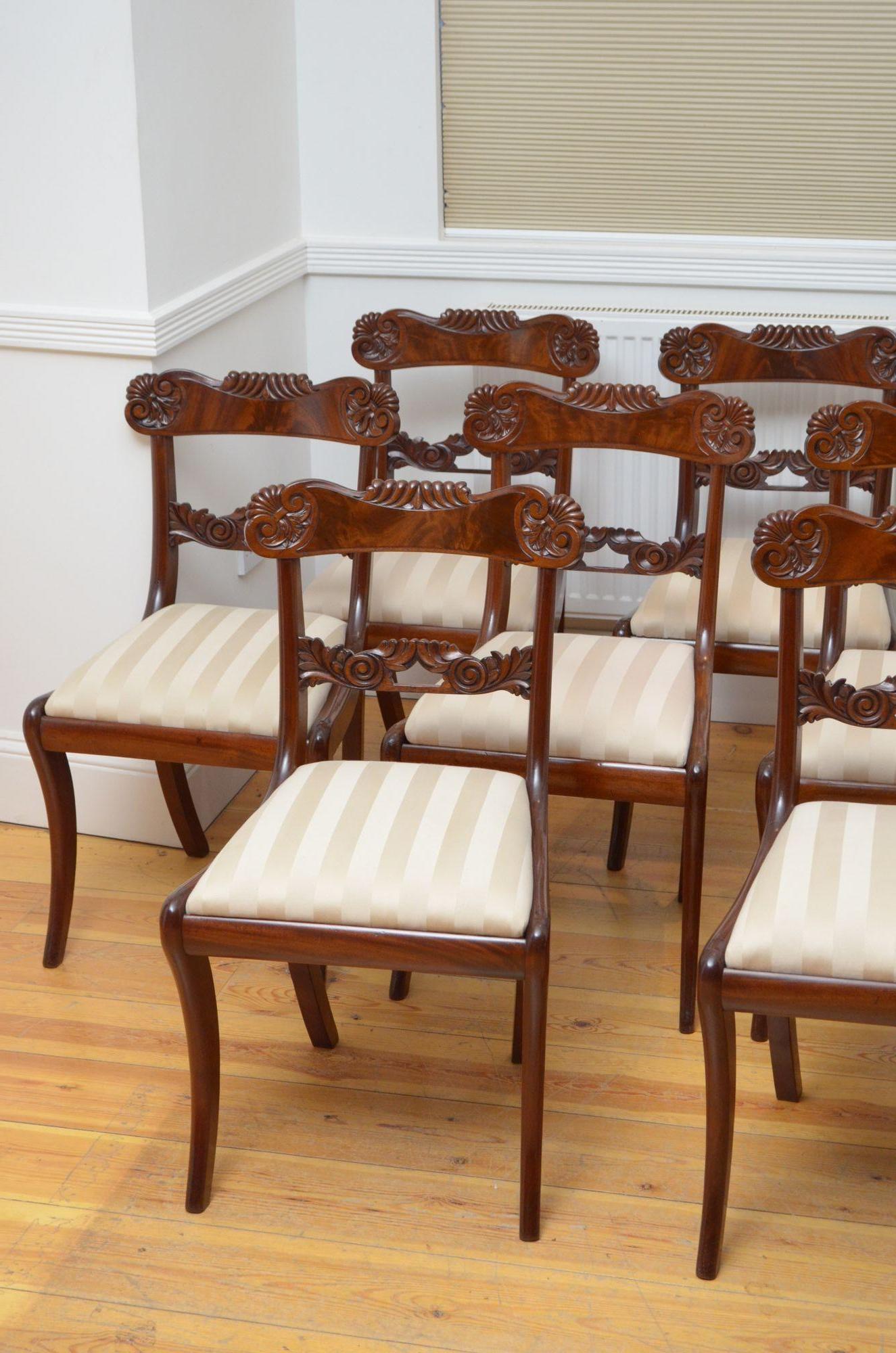 Sn4893 Fine quality set of twelve William IV dining chairs in mahogany, each chair having flamed mahogany top rail with fleur de lis carving and scroll carved mid rail above drop in seat covered in stripy cream fabric, all standing on saber legs.