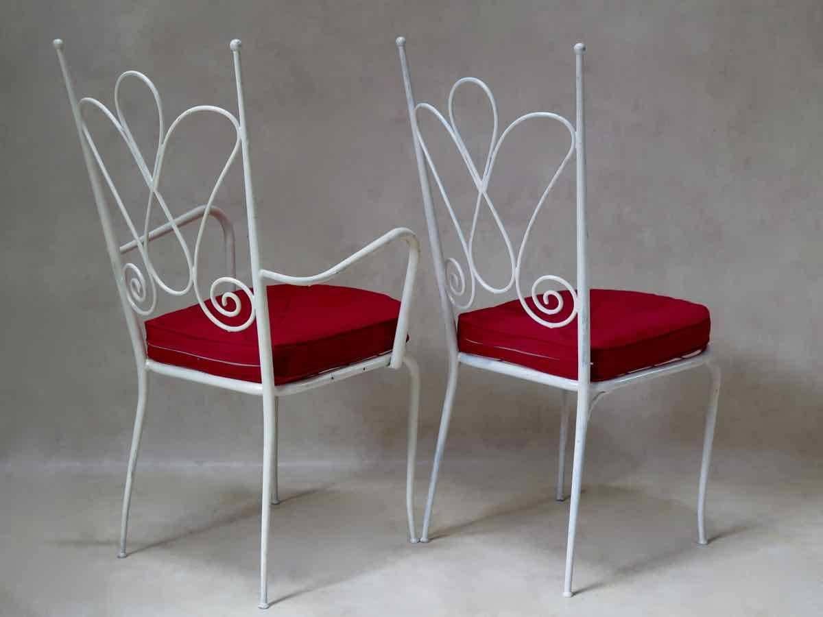 Elegant, wide and comfortable set of seven chairs and six armchairs from the 1950s. Made of sturdy but light tubular metal, painted white. Criss-crossed iron seat bases. The cushions are upholstered in red outdoor canvas.

Dimensions provided