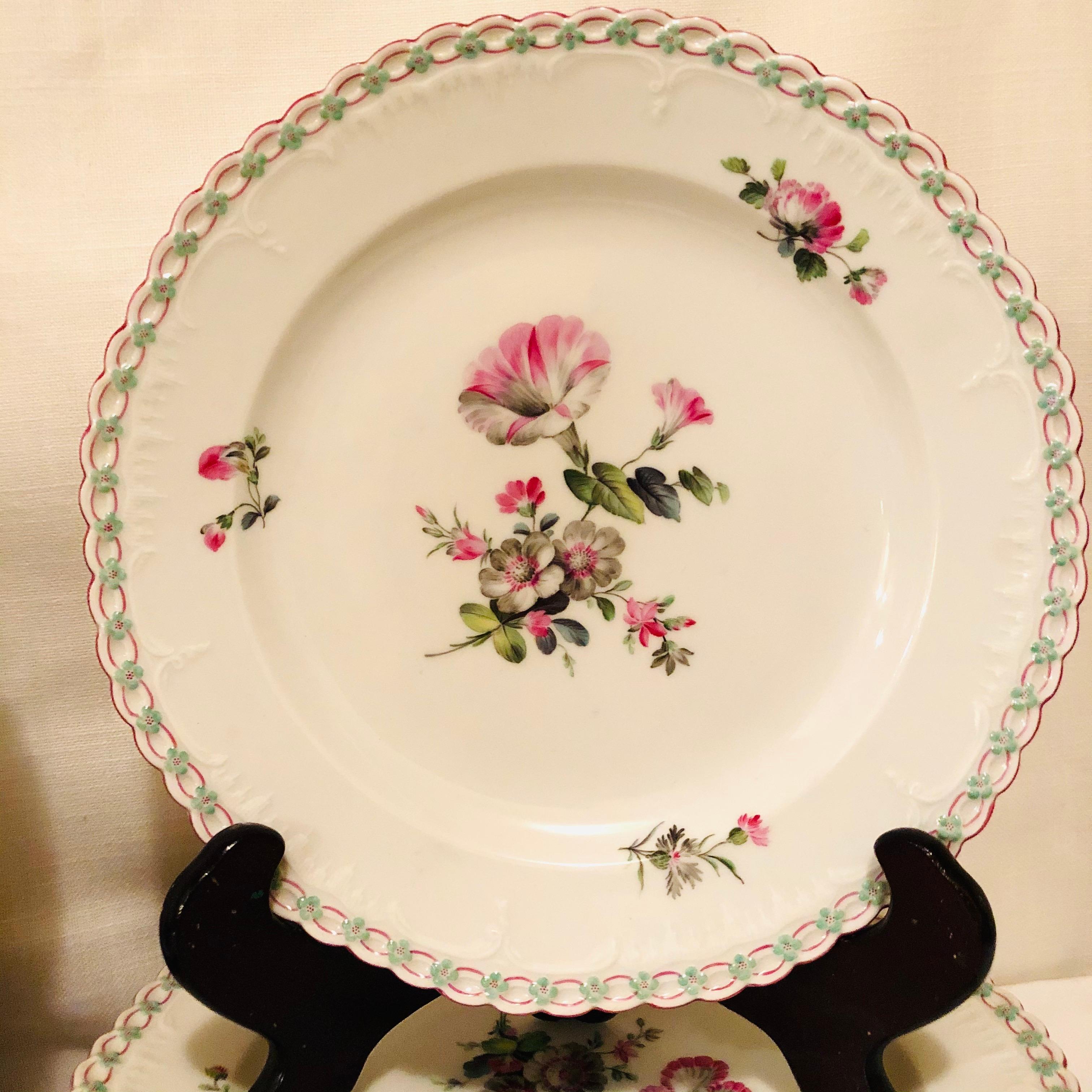 Set of thirteen KPM dinner plates, each painted with different pink and green flower bouquet, with raised forget me nots. The border is fluted and has a pink oval design with blue raised forget me nots. These can be used on your table setting as a