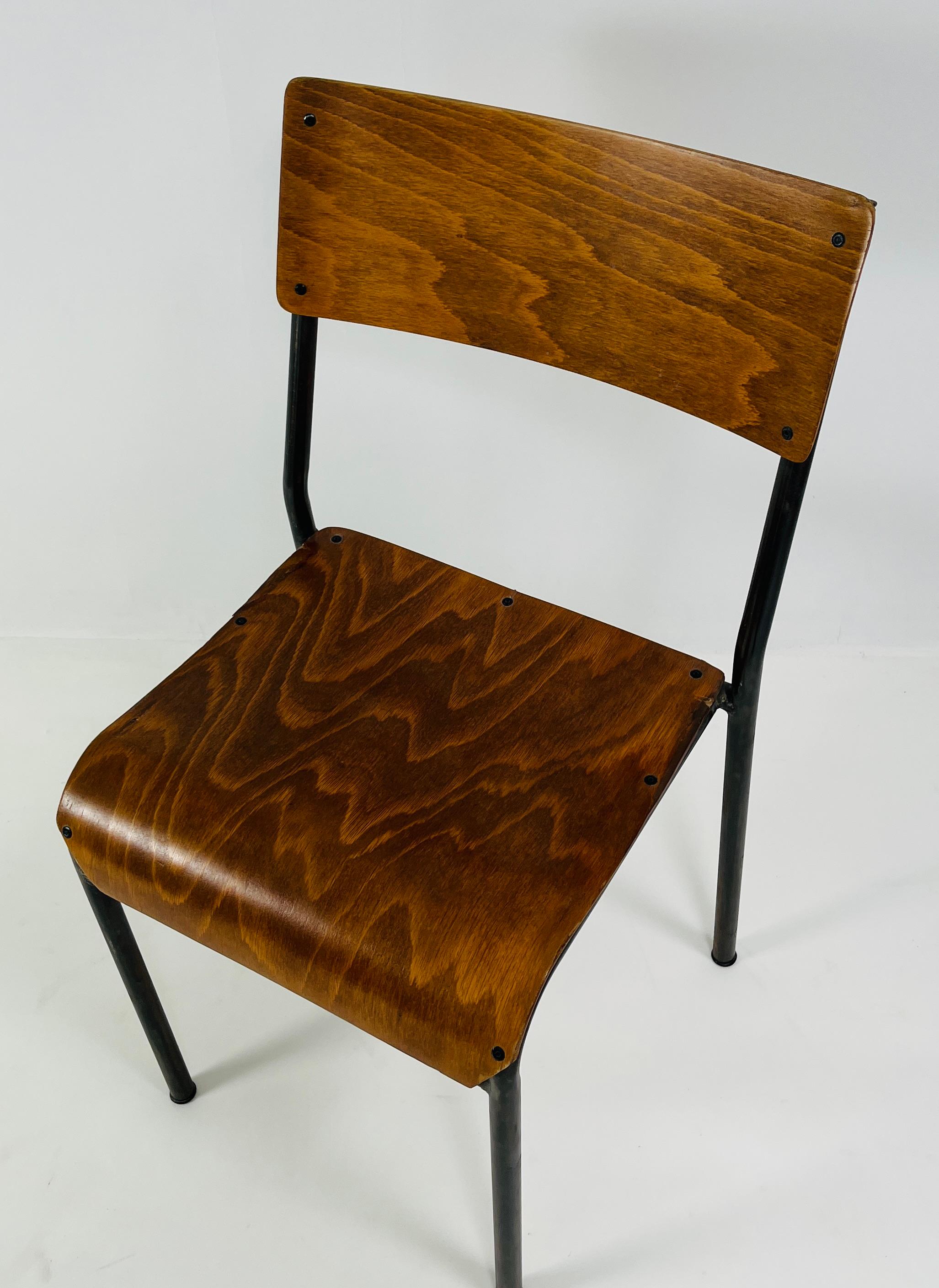 A striking ensemble of thirteen mid-century chairs from France, dating to the 1960s. Each features a molded plywood seat and backrest with warm, expressive grain, paired with a sleek steel frame finished in a handsome gunmetal patina. Their