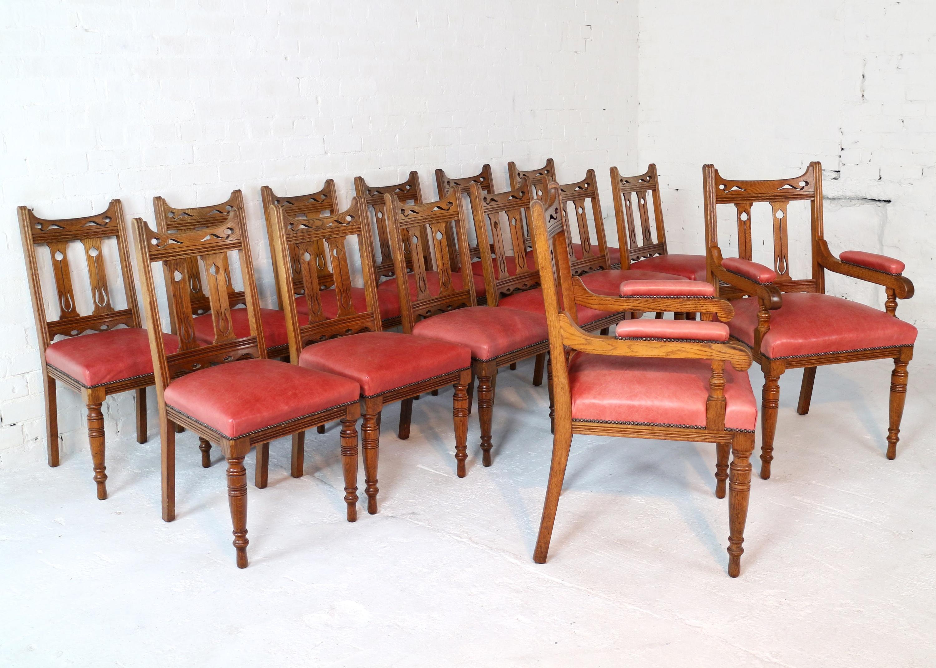 Un ensemble très original de 14 chaises de salle à manger en chêne doré Arts & Crafts du 19e siècle, probablement de Liberty's ou de Wylie & Lochhead. Comprenant 12 chaises d'appoint et deux fauteuils carver, ils présentent une traverse supérieure
