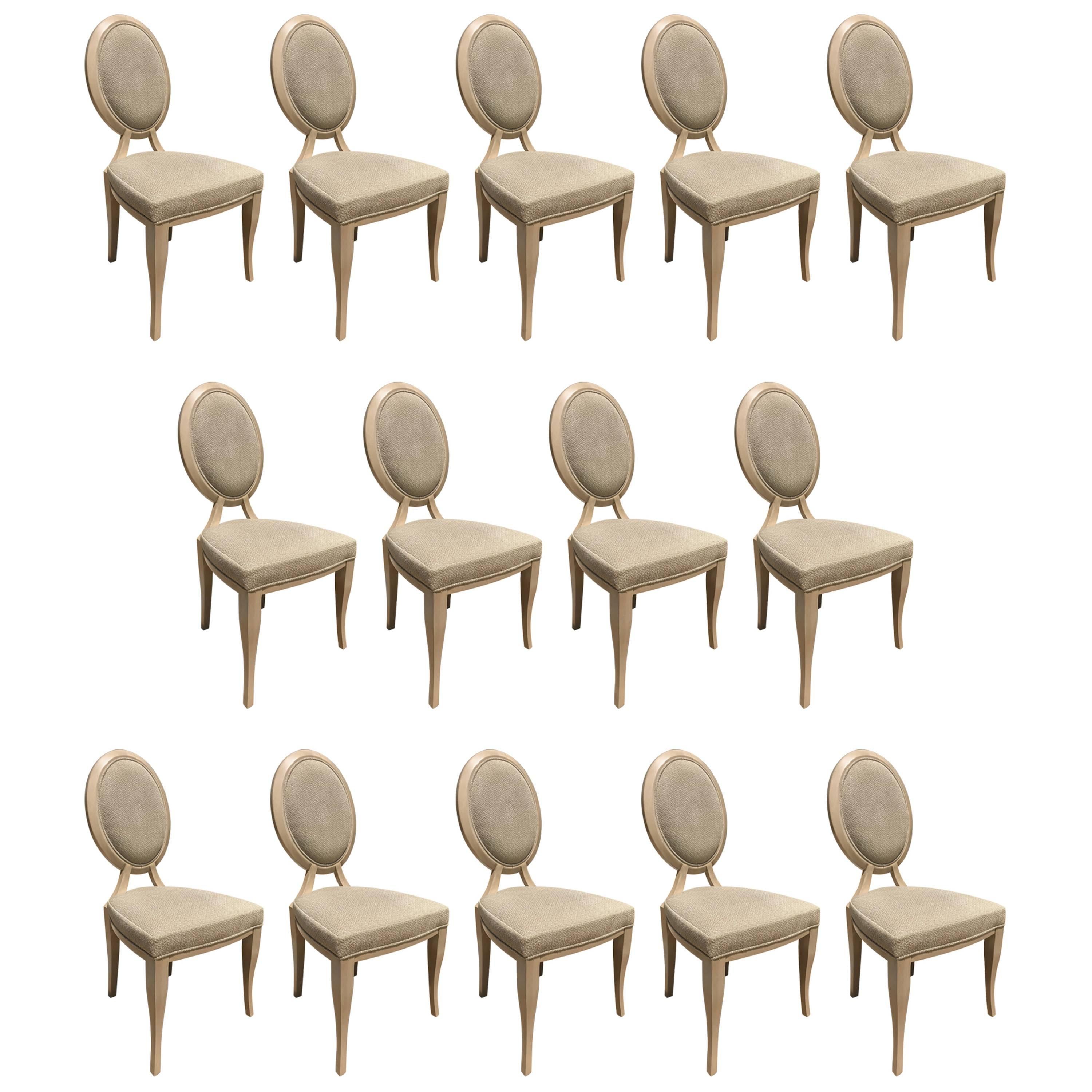 An elegant large set of 14 oval back dining chairs in stained hardwood by Reagan Hayes. They are almost unused and exquisitely upholstered in Beacon Hill Flashpoint/Silverscreen fabric on seat and inside back, the outside back is covered in Kravet