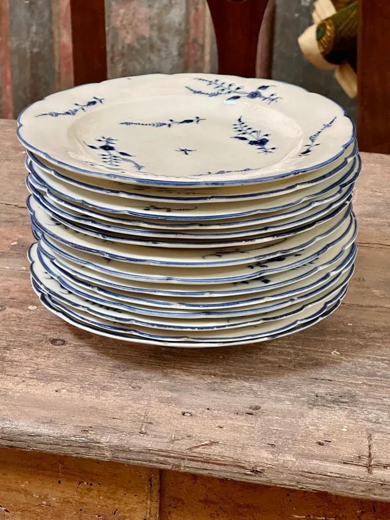 Set of 14 French 18th century soft paste porcelain Chantilly Blue Sprig Plates dinner plates in the Blue Sprig pattern with blue underglaze floral and foliage design and blue rim, marked on reverse of each plate with the fanfare trumpet mark in