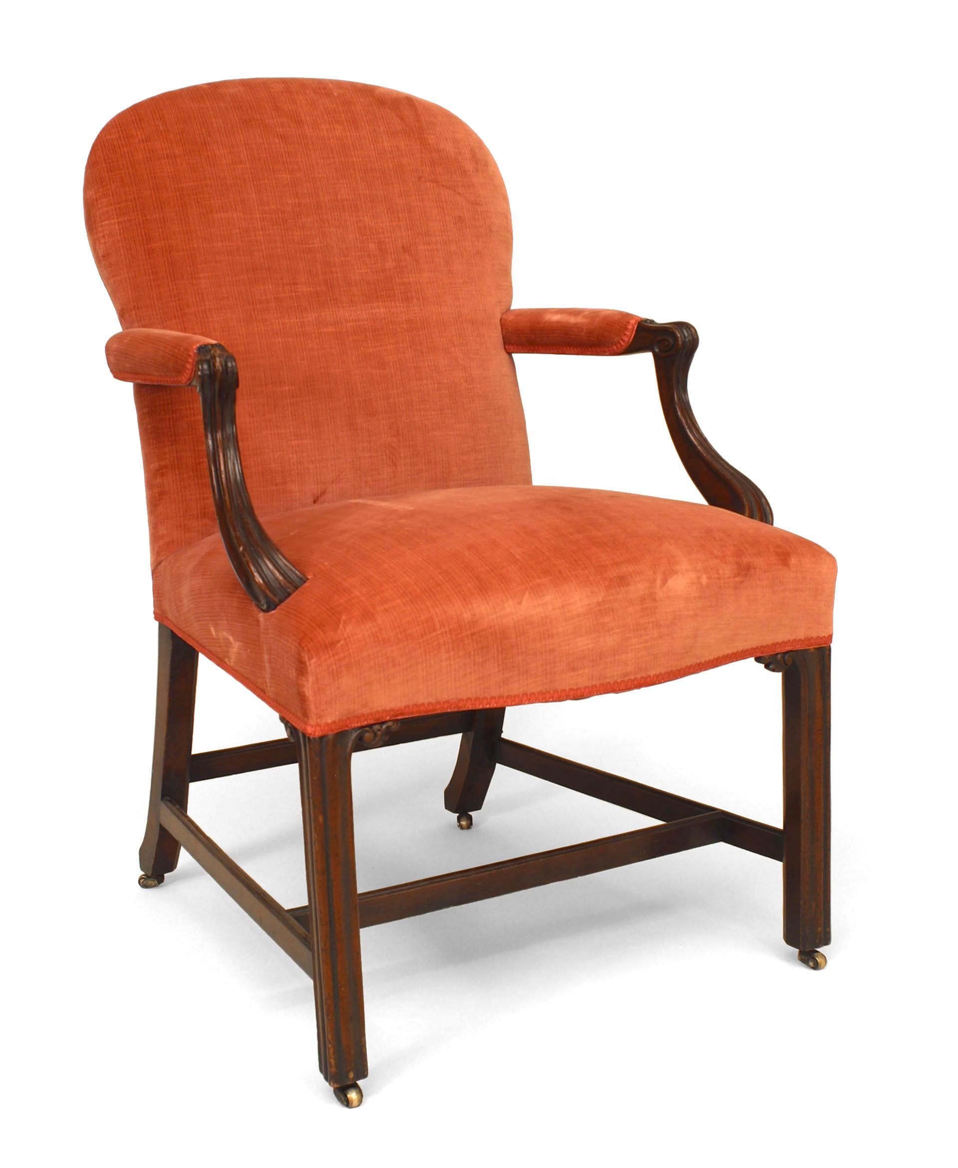 Set of fourteen Georgian mahogany chairs including ten side chairs and four armchairs. Each chair is upholstered in salmon-colored velvet and features a rounded back and seat, carved corners, and a rectangular stretcher base.