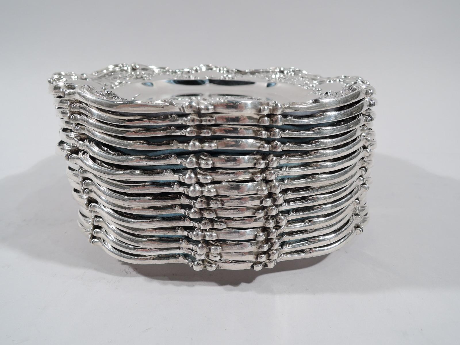 Set of 14 Edwardian Rococo sterling silver bread and butter plates. Made by Gorham in Providence in 1912-1913. Each: Shaped well and scrolled and wavy rim. Shoulder has chased garlands alternating with scrolled frames (vacant). Fully marked