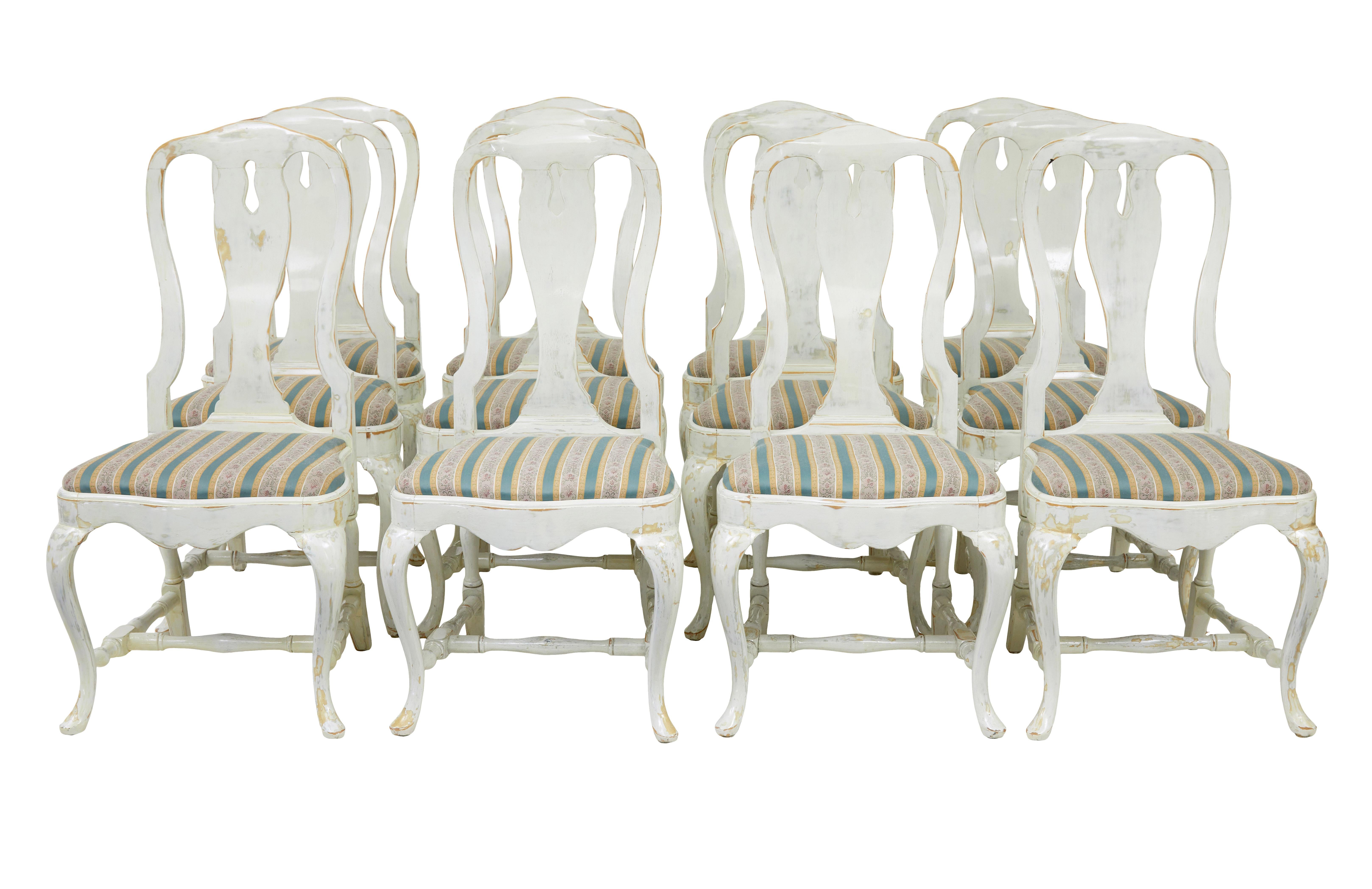 Conjunto de 14 sillas de comedor lacadas de influencia Queen Anne de hacia 1920.

El juego consta de 12 sillas individuales y 2 sillones tallados.  Fabricada en haya y posteriormente pintada de blanco, esta pintura se ha frotado en algunas partes