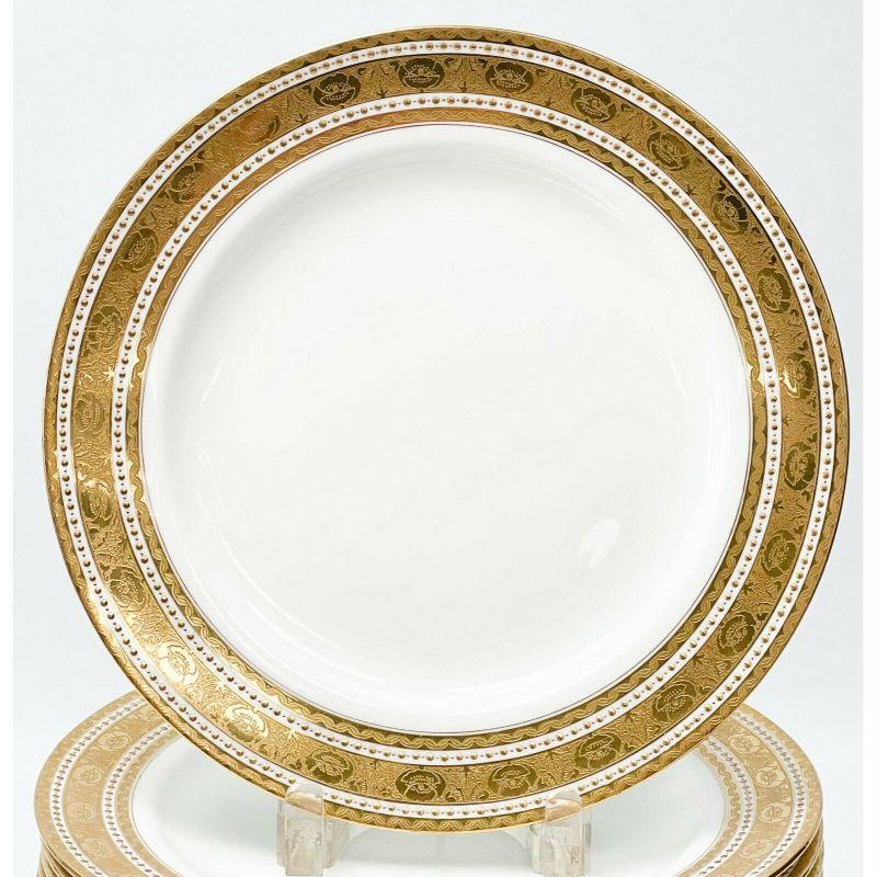 Set of 14 Minton England Gilt Porcelain dinner plates in H1417, 1910

A white ground to the center, ornate gilt decoration to the edge featuring florals and twisted ribbons. Bands of raised gilt dot decoration. Underside with Minton