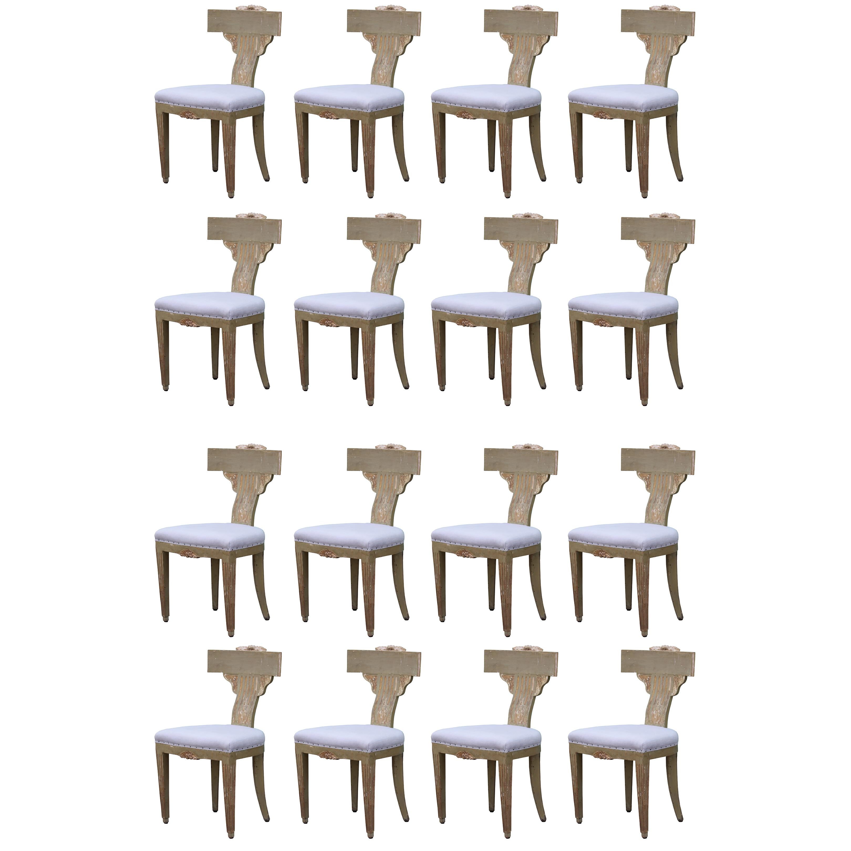 Set of 16 Hollywood Regency painted and carved Klismos dining chairs that we believe may be Italian or Swedish from the 19th century. These have the perfect amount of paint missing and wear. Need to be reupholstered.