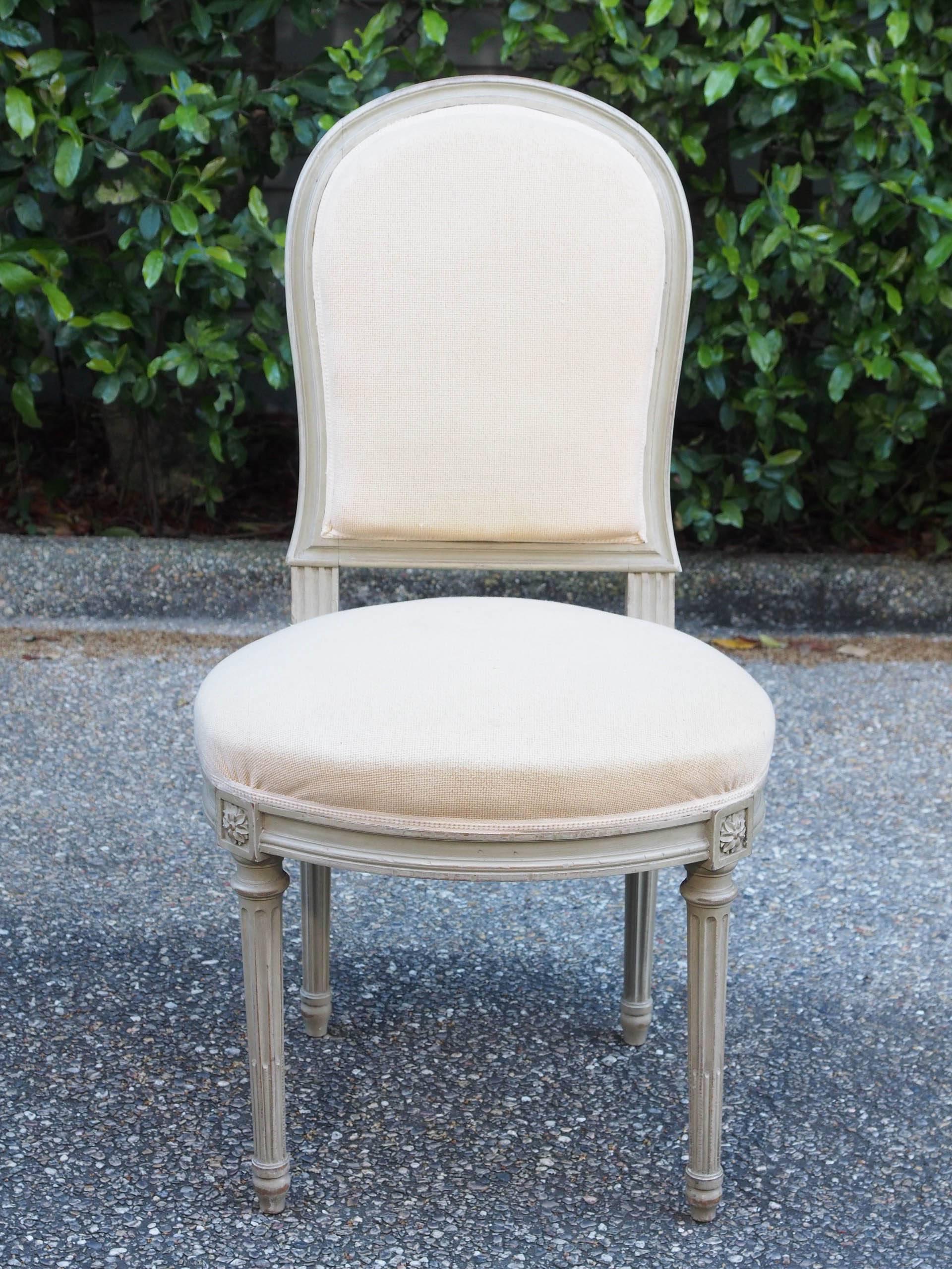 French Louis XVI style carved and painted dining chairs with arched backs over shaped seats.