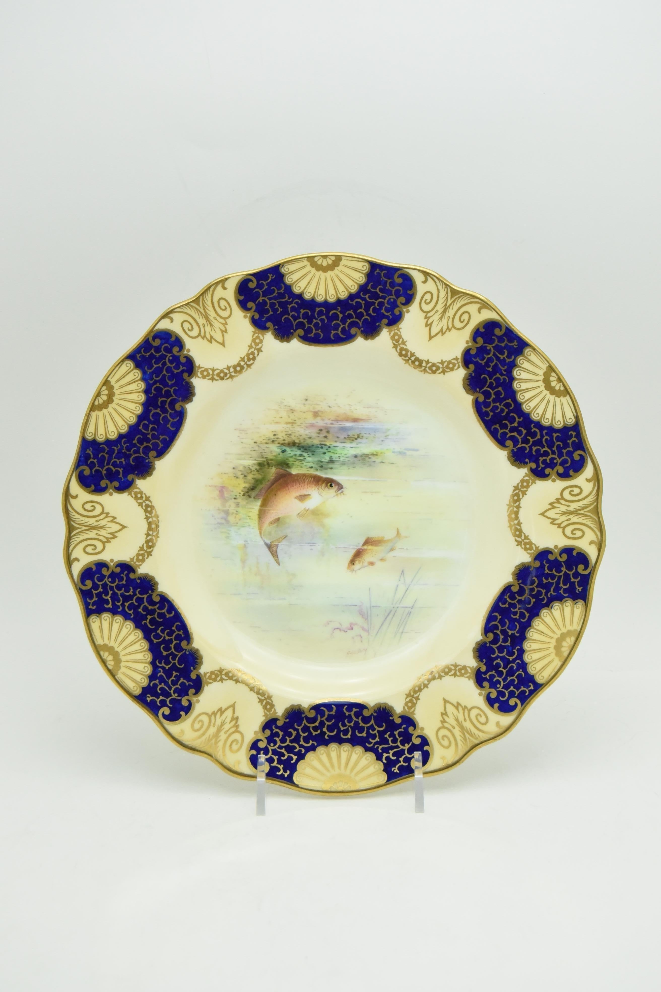 This is a large set of 16 hand painted and artist signed A. Holland, one of Wedgwood's famous and iconic artists. These fish plates are decorated with an unusual border incorporating cobalt blue with pale ivory/caramel and highlighted with a