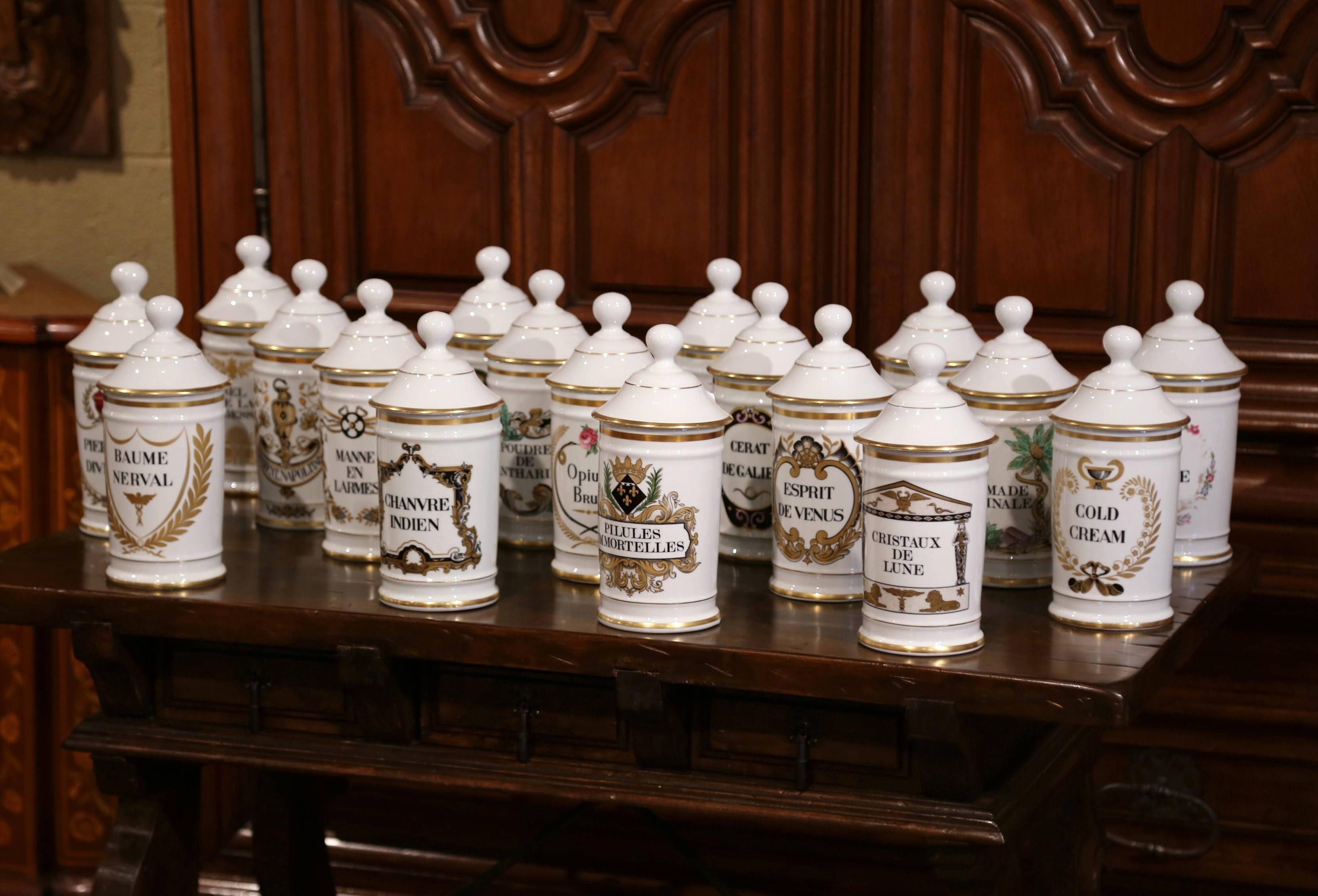 This set of 18 pharmaceutical bottles was created in Limoges, France, circa 1960. Each colorful porcelain jar with hand painted decor, features an apothecary recipe written in French on the front, and is further embellished with gilt accent on the