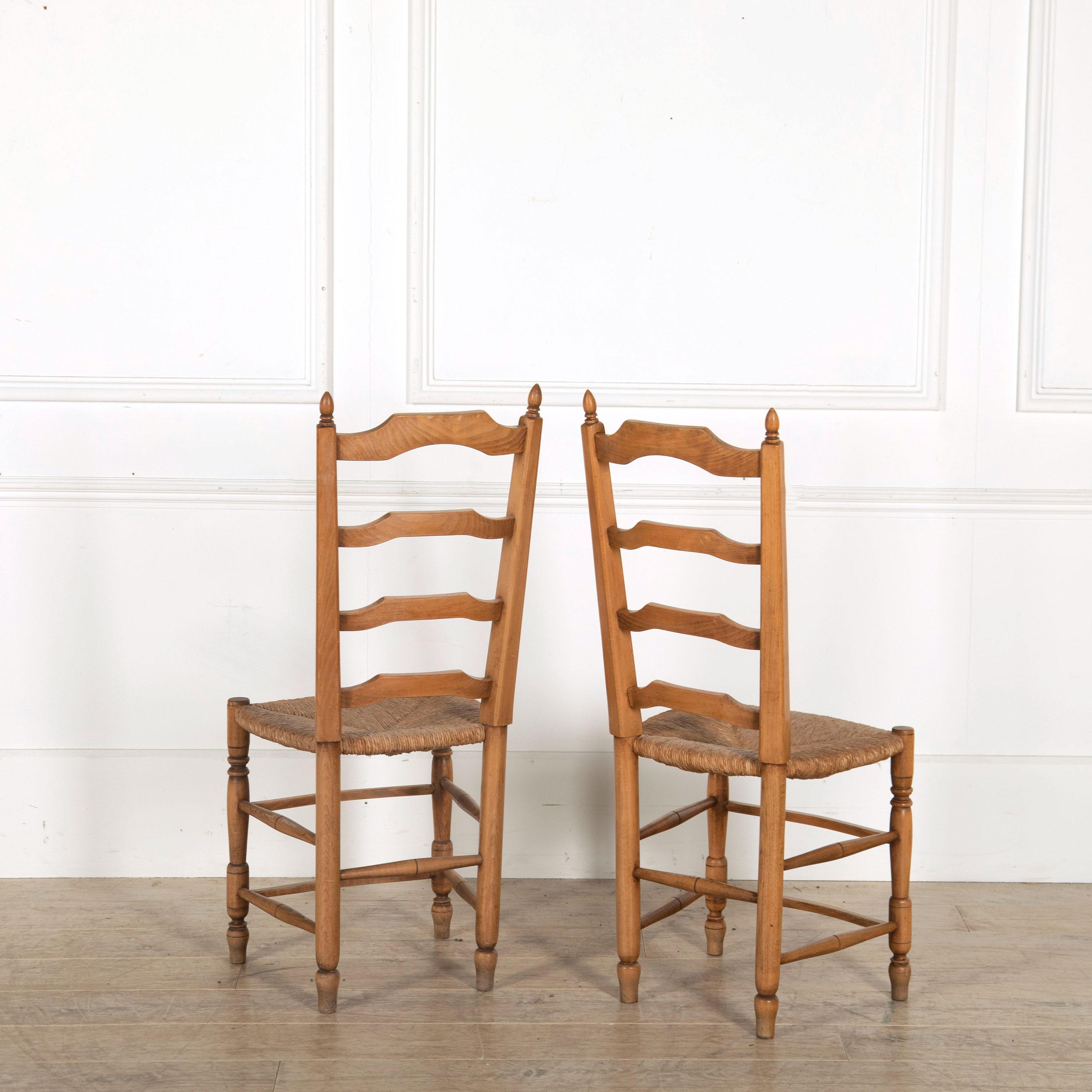 A set of 18 French fruitwood dining chairs with a ladder type back and rush seats, circa 1900.