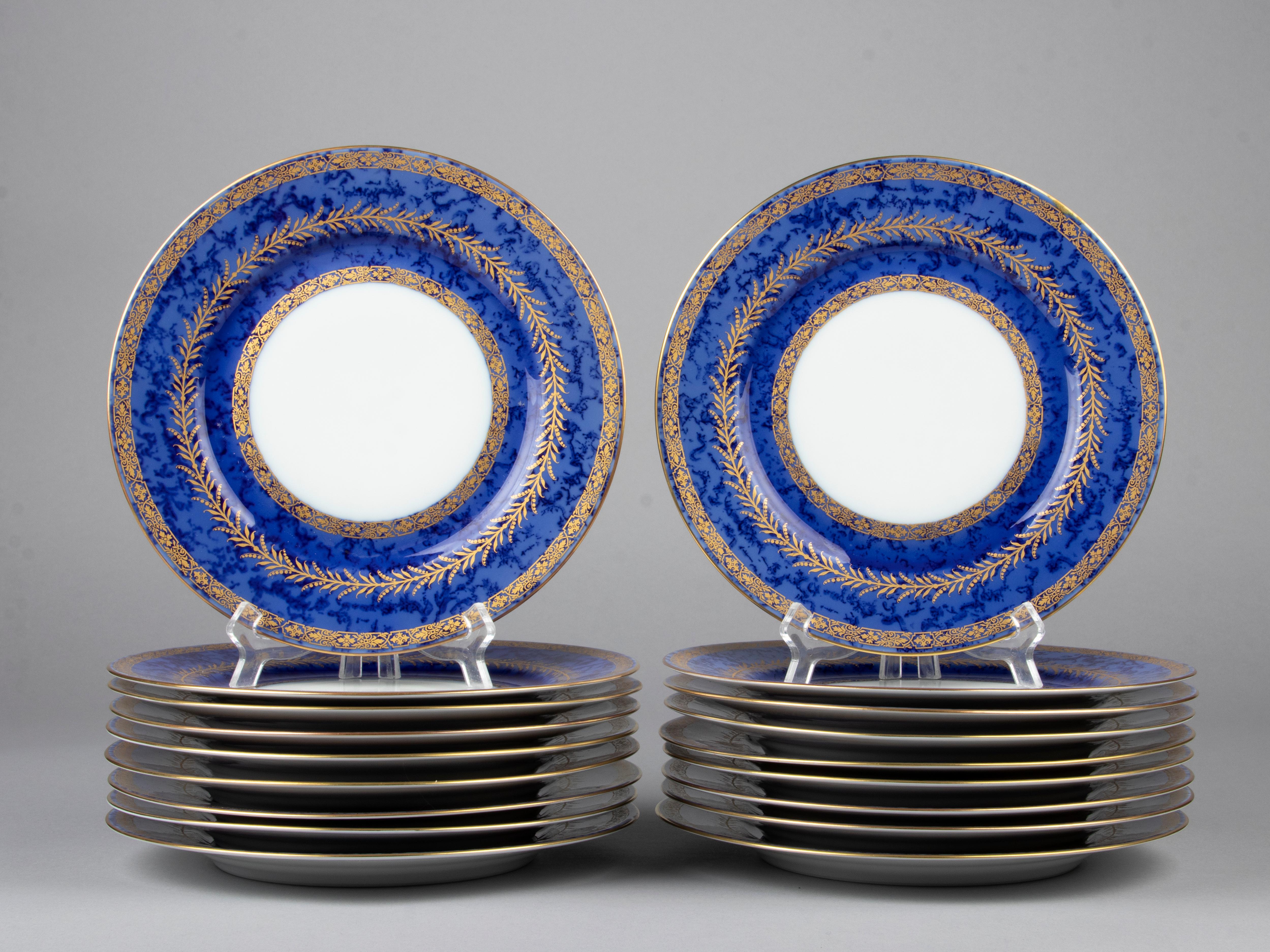Magnifique ensemble de 18 assiettes plates en porcelaine de la marque française Raynaud Limoges. Les assiettes sont d'un bleu profond, avec une sorte de motif nuageux, décoré d'accents dorés. Le service est réalisé par Raynaud Limoges. Au dos des