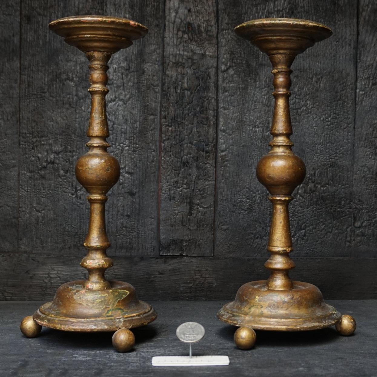 Beautiful old set of two large 18th century French polychromed candlesticks. Multiple layers of bois doré or gold paint were supposed to make the wood look very chique, and it did. 
Look how they aged. Ideal to burn rustic block candles on.