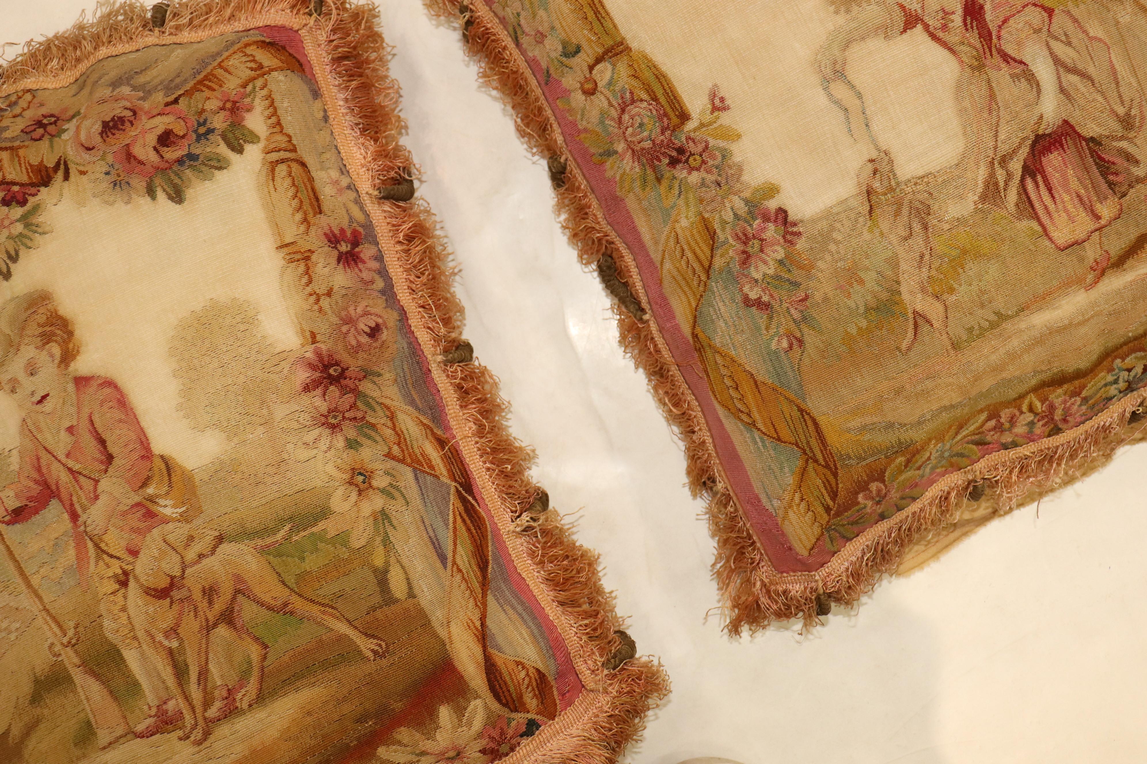 A set of late 18th century Aubusson tapestry pillows made with fine quality wool and silk. One pillow has Man with his dog while the other has a women with a small puppy. Backed in velvet. Each Measuring 21” x 21” individually. Both sewn shut.
 
 