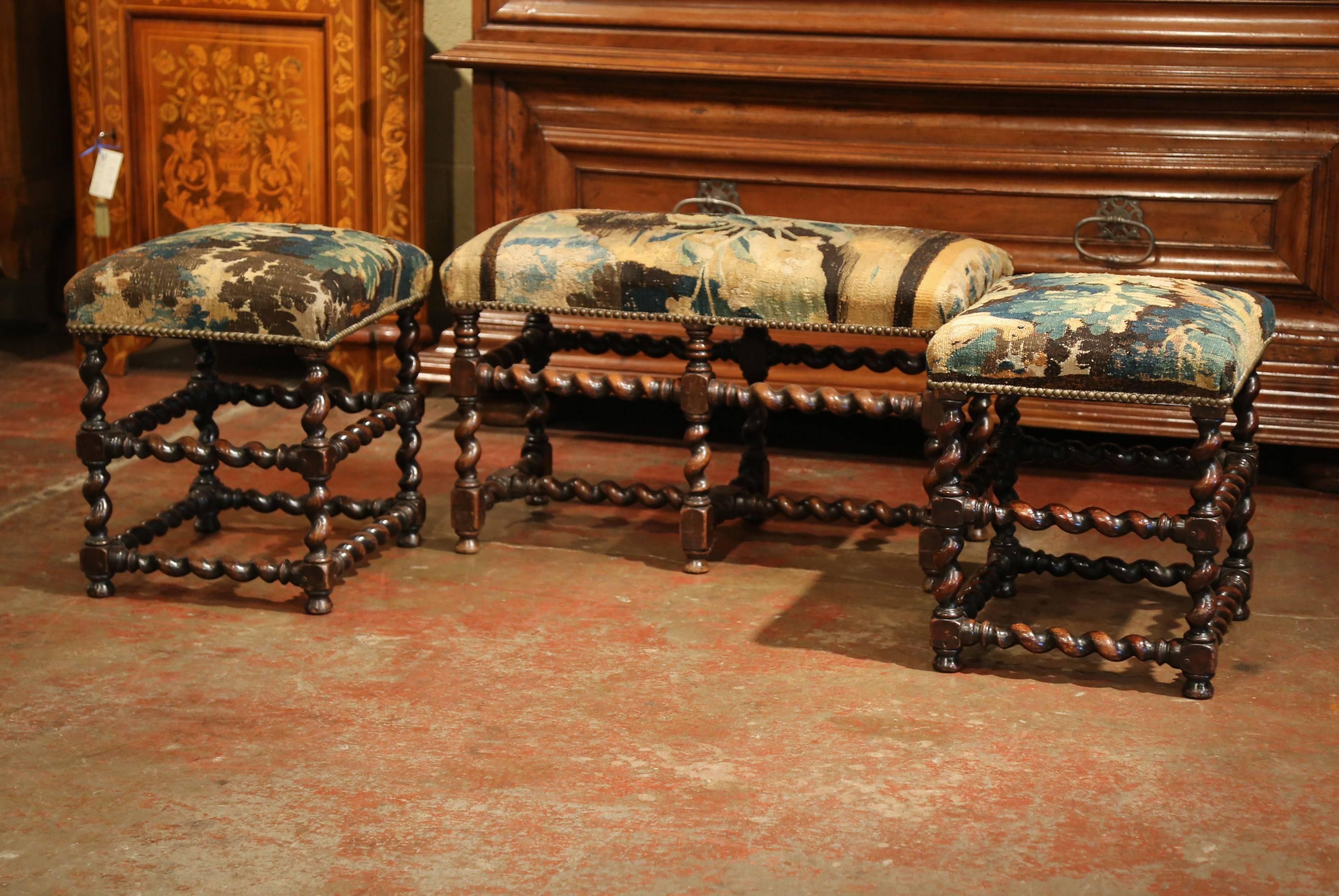Decorate a den with this elegant pair of antique stools with matching bench. Crafted in Southern France circa 1850, each fruitwood piece stands on barley twist legs with matching stretcher, and is upholstered with 18th century verdure Aubusson