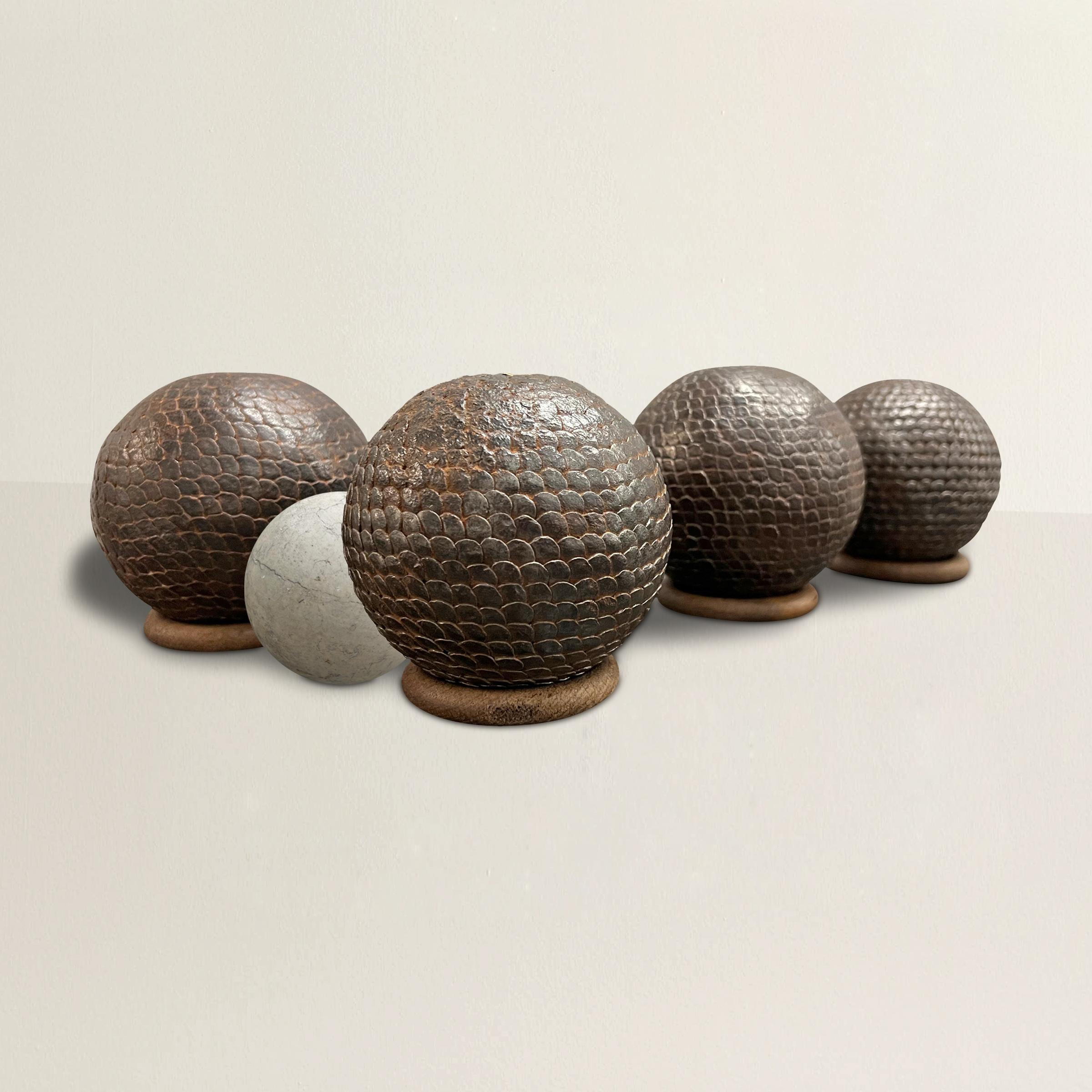 Ensemble ludique de boules de pétanque françaises du XIXe siècle, composé de quatre boules cloutées en fer et d'un cochonnet en marbre.  L'ensemble peut être utilisé en jeu, mais nous avons inclus des anneaux en bois pour les plus grandes boules