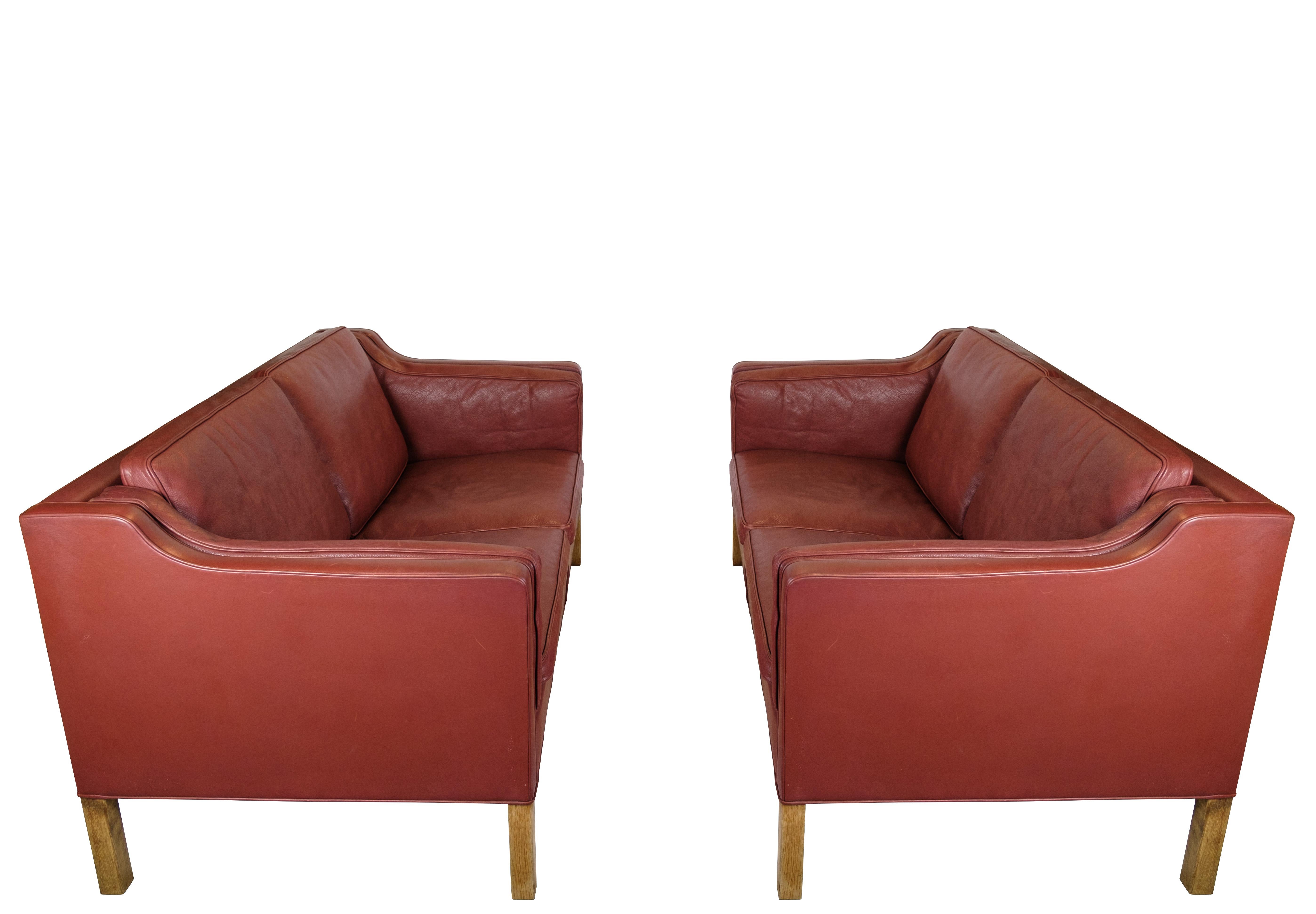 Ensemble de 2 canapés à deux places, modèle 2212, conçu par Børge Mogensen pour Fredericia Stolfabrik dans les années 1960. Les canapés sont recouverts de cuir rouge et ont un cadre en chêne. Leur design simple et intemporel allie confort et
