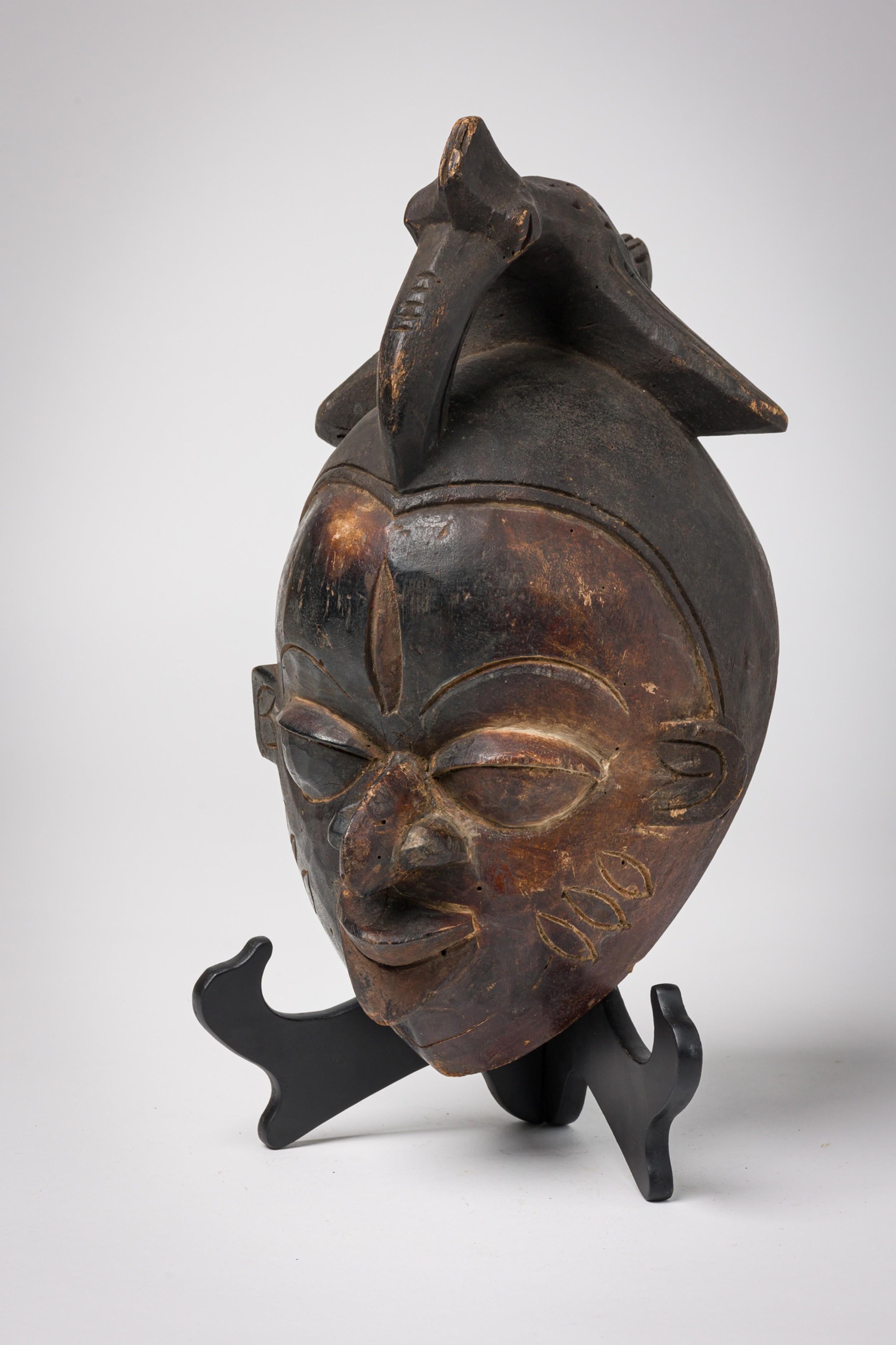 Ensemble de 2 masques Bamileke en bois sculpté du Cameroun du 20e siècle, avec un sommet en forme de calao, habituellement portés par les guerriers, les membres de la famille royale et les personnes fortunées. (PRIX DE L'ENSEMBLE)

Bon, avec des