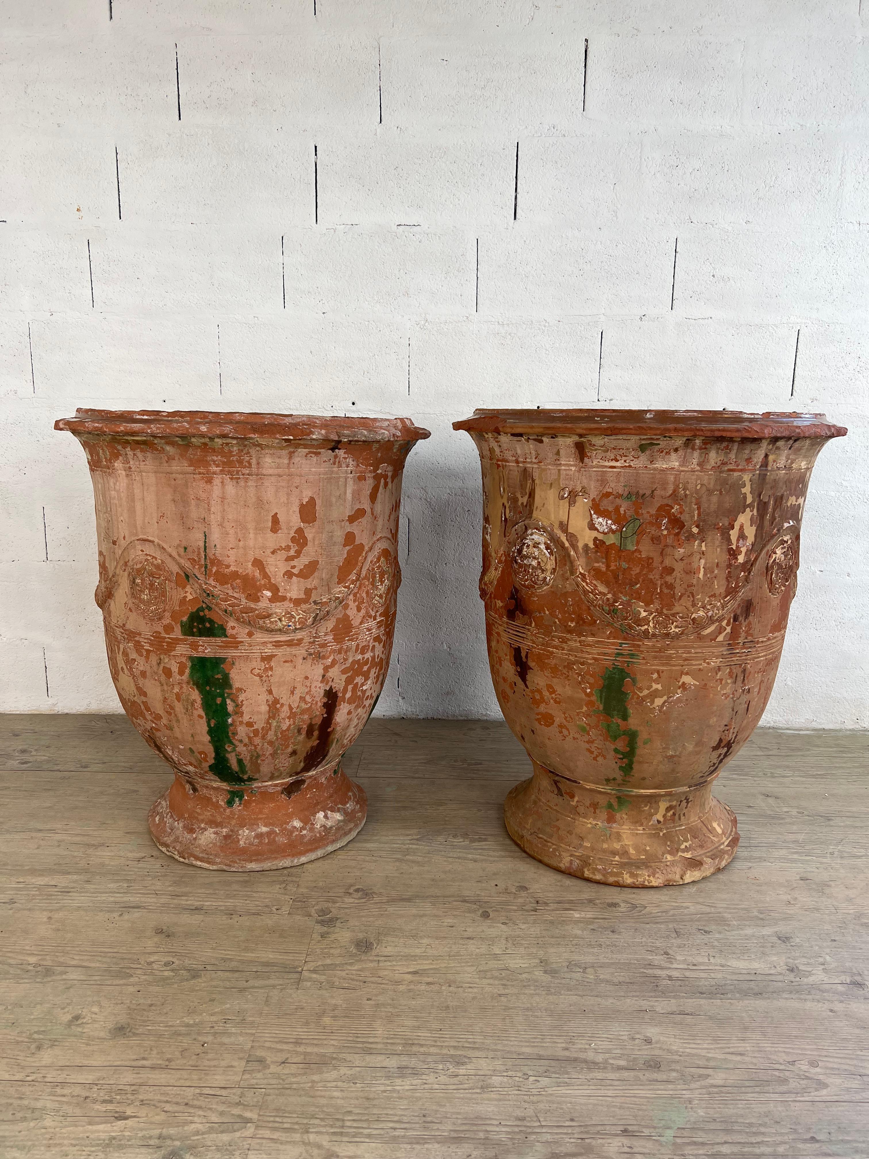 Cette rare et monumentale paire de vases d'Anduze du XIXe siècle, fabriqués par la célèbre manufacture Boisset, incarne le riche héritage de l'art des jardins français. L'un des vases porte la signature sculptée de Boisset, une marque d'authenticité