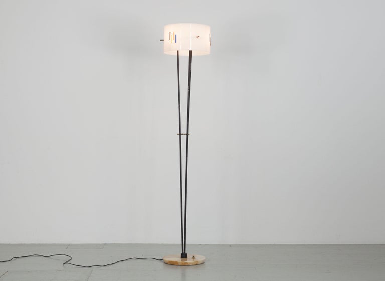 Italian floor lamp from the 60s. The shade of the lamp is made of white Perspex and decorated with a classic 60s pattern in yellow, red, blue and black. The steel frame is painted black and sits on a marble base. The lamp has three E27 sockets. The