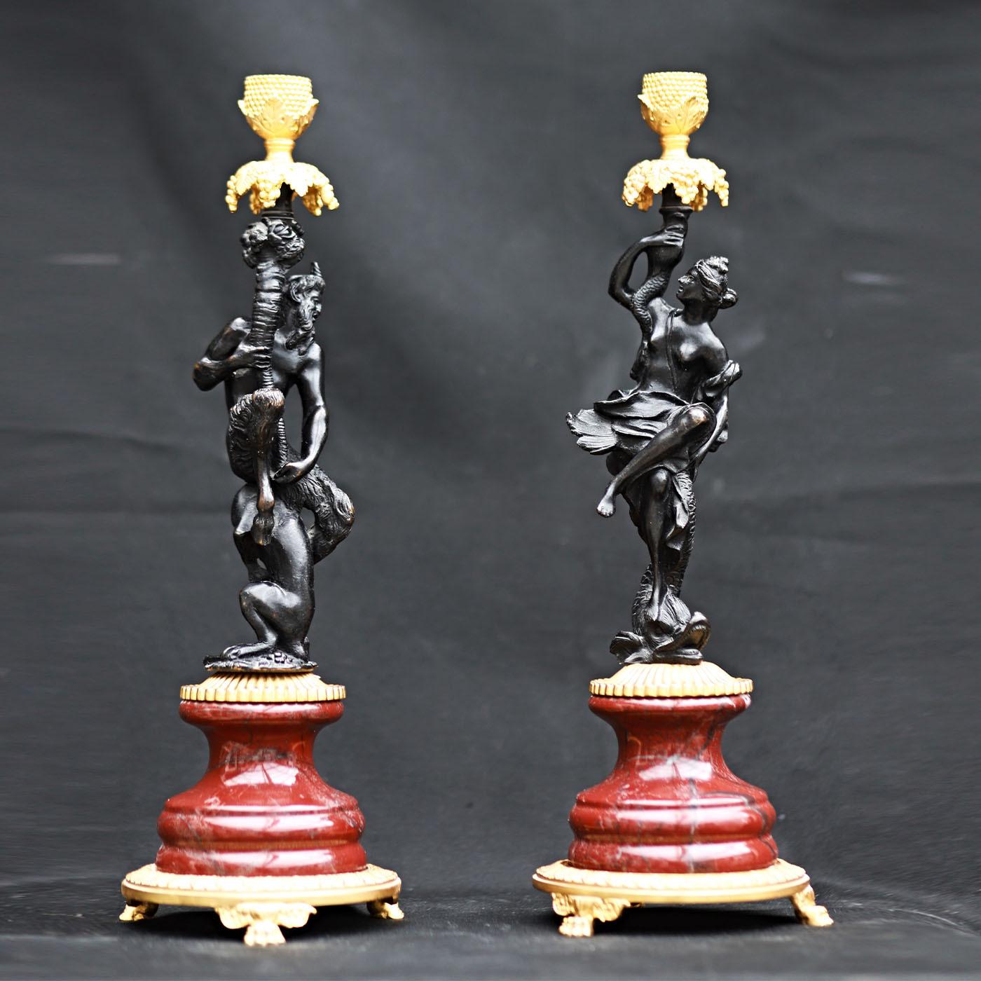 Die beiden skulpturalen Kerzenständer dieses Sets zeichnen sich durch eine kostbare Silhouette aus, die handgemeißelte Bronzestatuetten mit Messing und feinem Rosso Levanto-Marmor kombiniert. Die anthropomorphen Figuren, ein Faun und eine Magd, sind