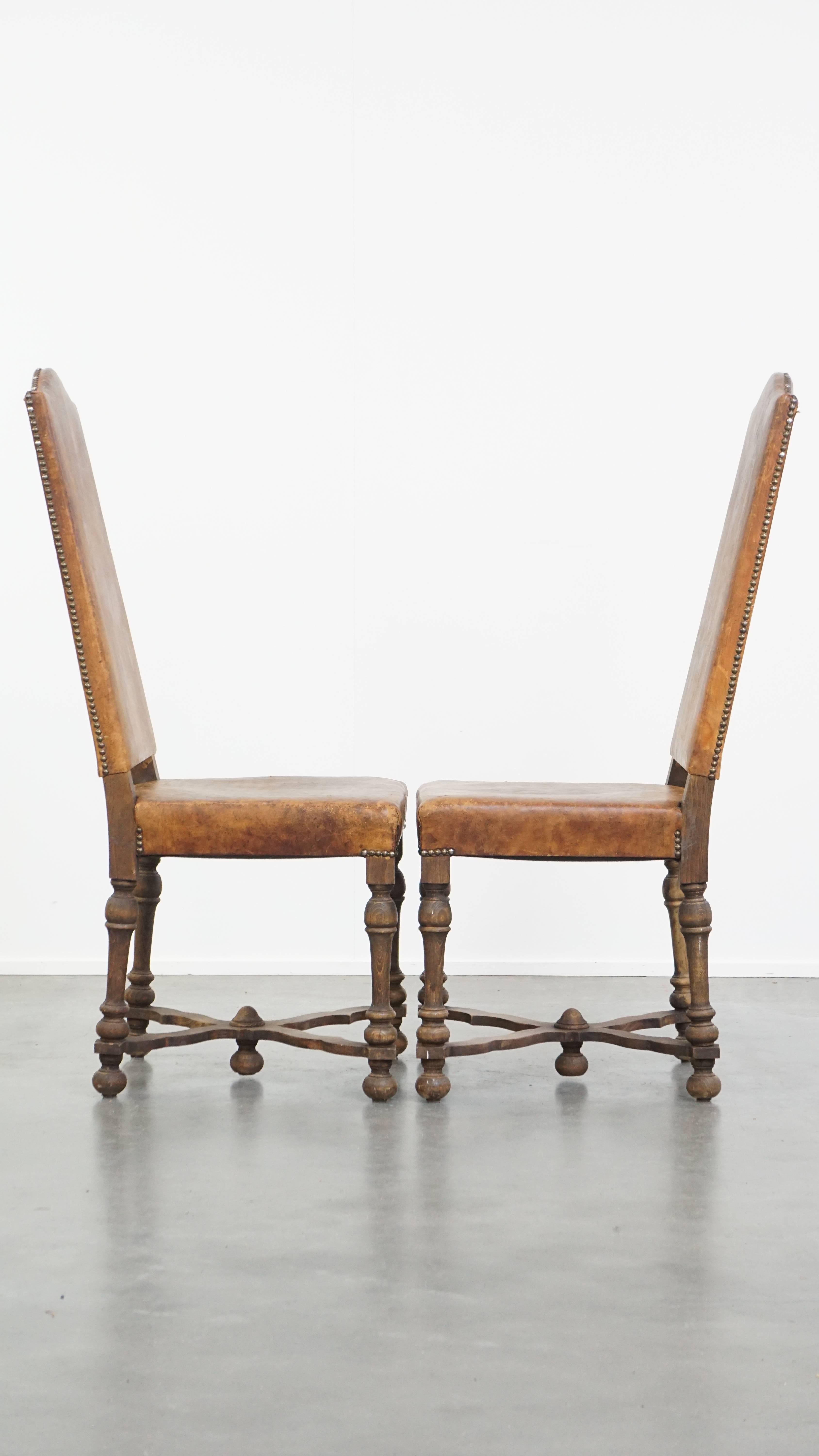 Offered here is this set of 2 antique wooden and sheepskin leather dining chairs with a beautiful patina, dating from the early 1900s. These fantastic antique chairs have a striking character and are true eye-catchers. Originating from the early