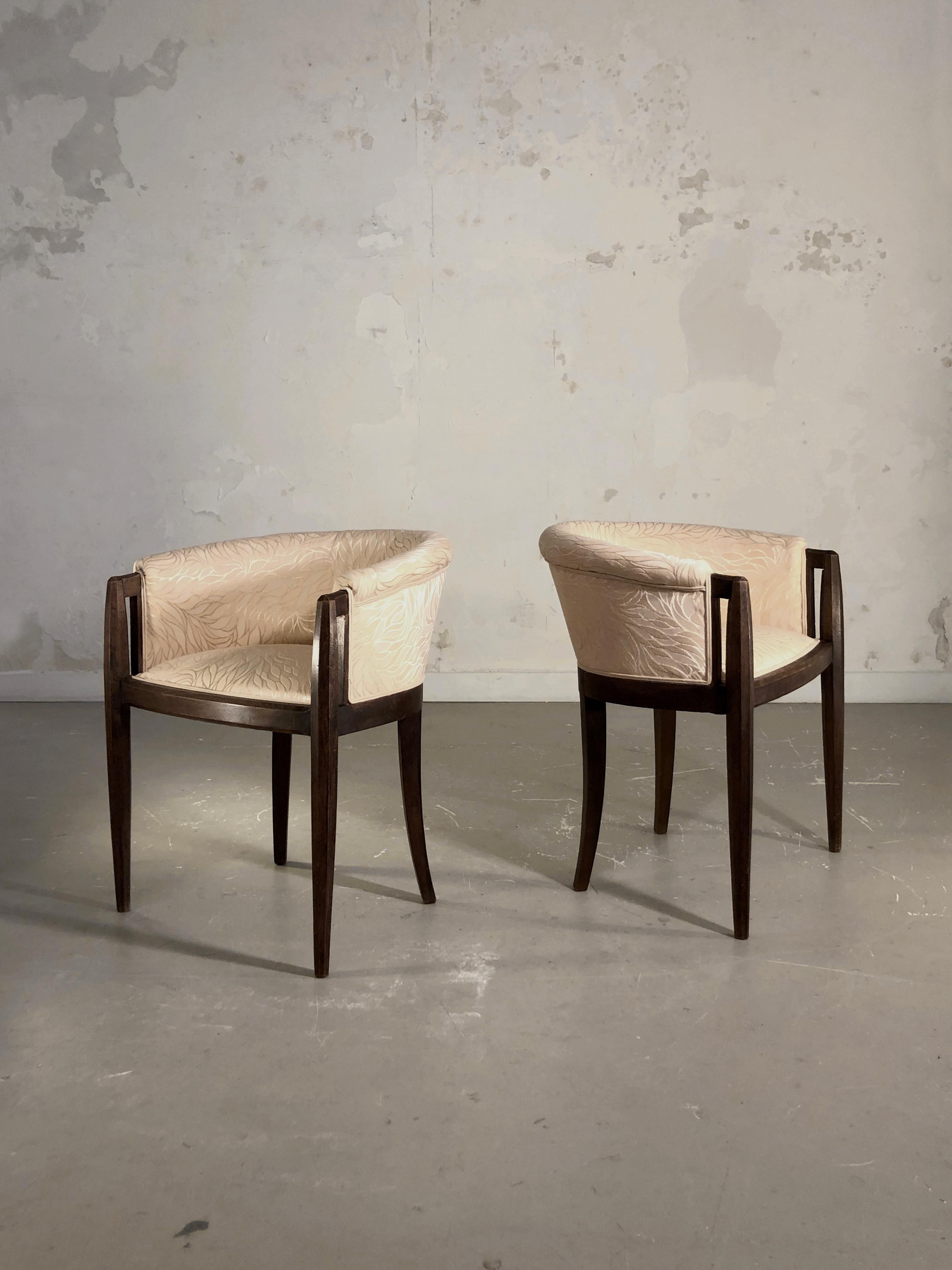 A pair of 2 luxurious art deco chairs in the spirit of Jacques Emile Ruhlmann, France, 1930. Massive dark wood structures with beautiful curved and ovoïd lines are giving these chairs a warm sensual feel, increased by a comfortable seating area with