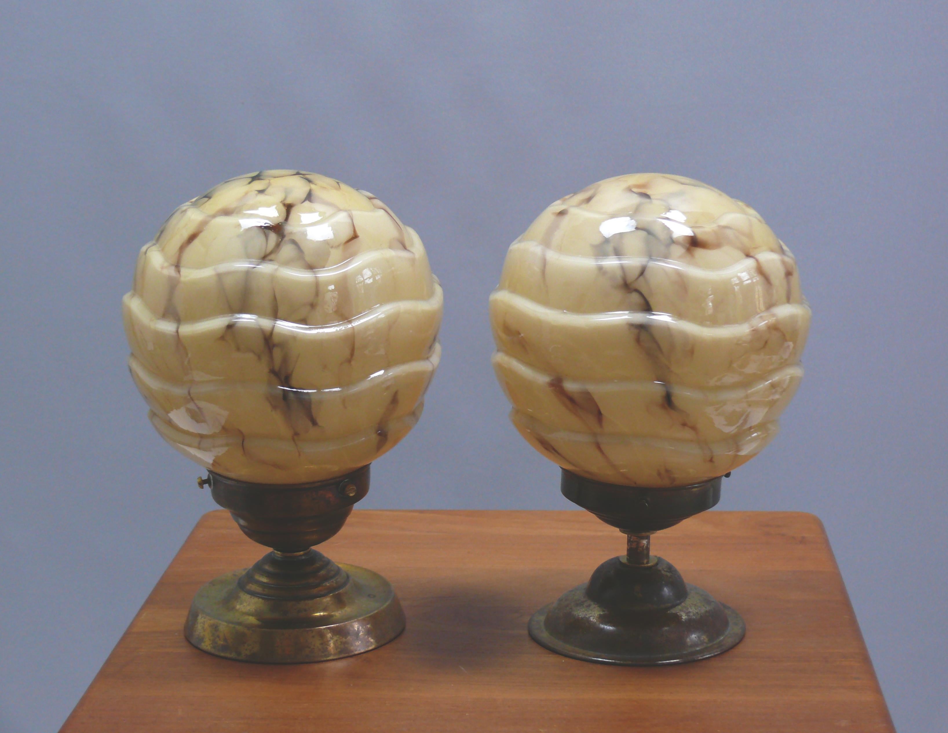 Ensemble de 2 élégantes lampes boules Art Déco avec suspension en laiton et abat-jour en verre marbré. L'abat-jour en verre beige est strié de bandes brunes et la surface est structurée. Les lampes datent de la première moitié du XXe siècle (1920 -