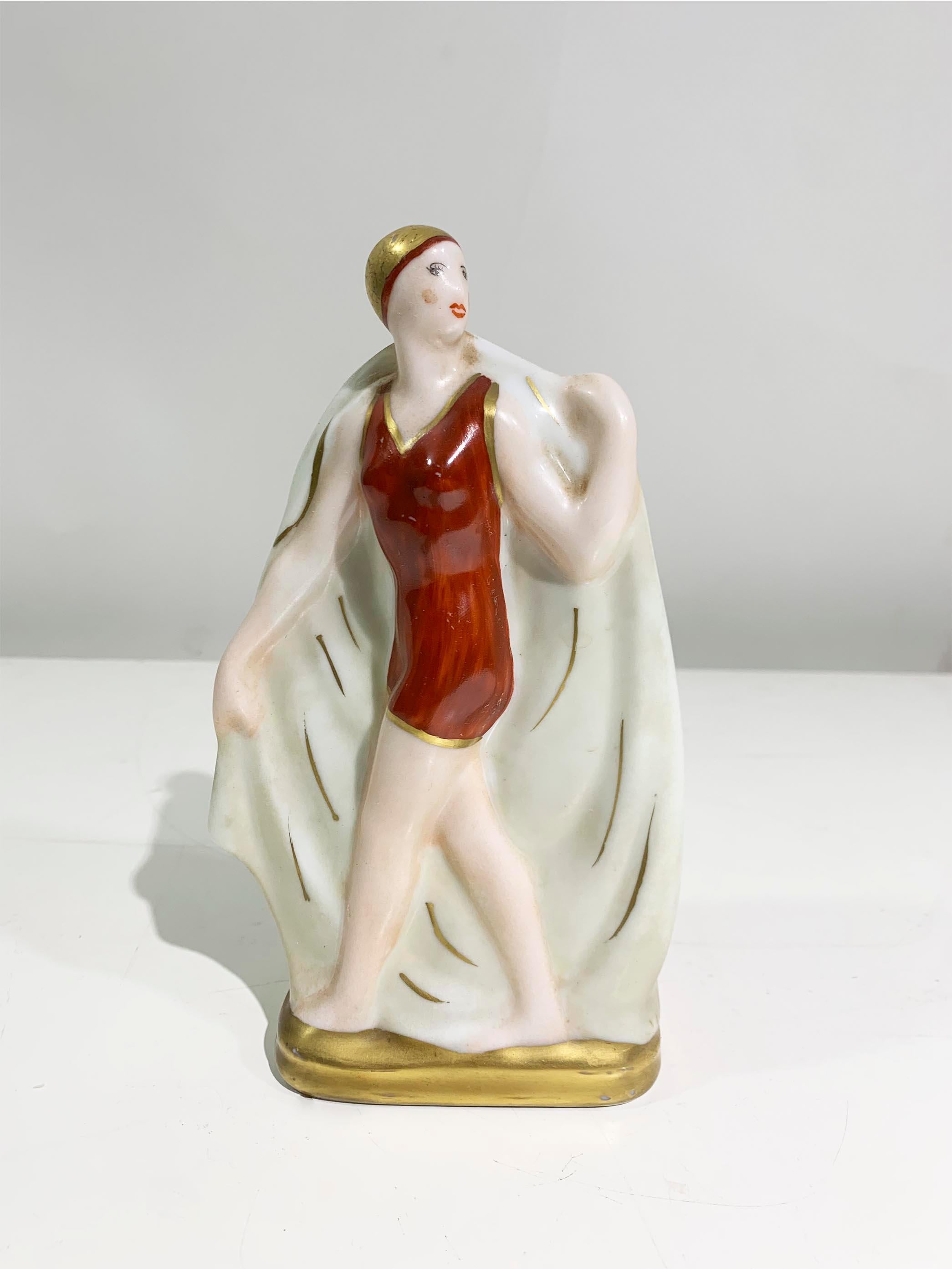 Art Deco Figurines in Limoges porcelain, featuring a depiction of 2 young women swimmers adorned in a classic bathing suit featuring a more fitted and tailored look compared to the loose and boxy styles of the previous decades. 
In a playful